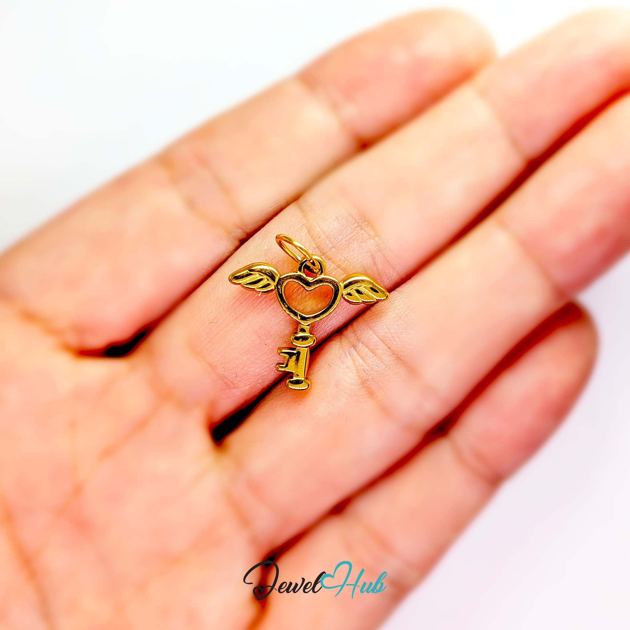 Winged heart key charm in gold stainless steel - held in the hand for scale - JewelHub