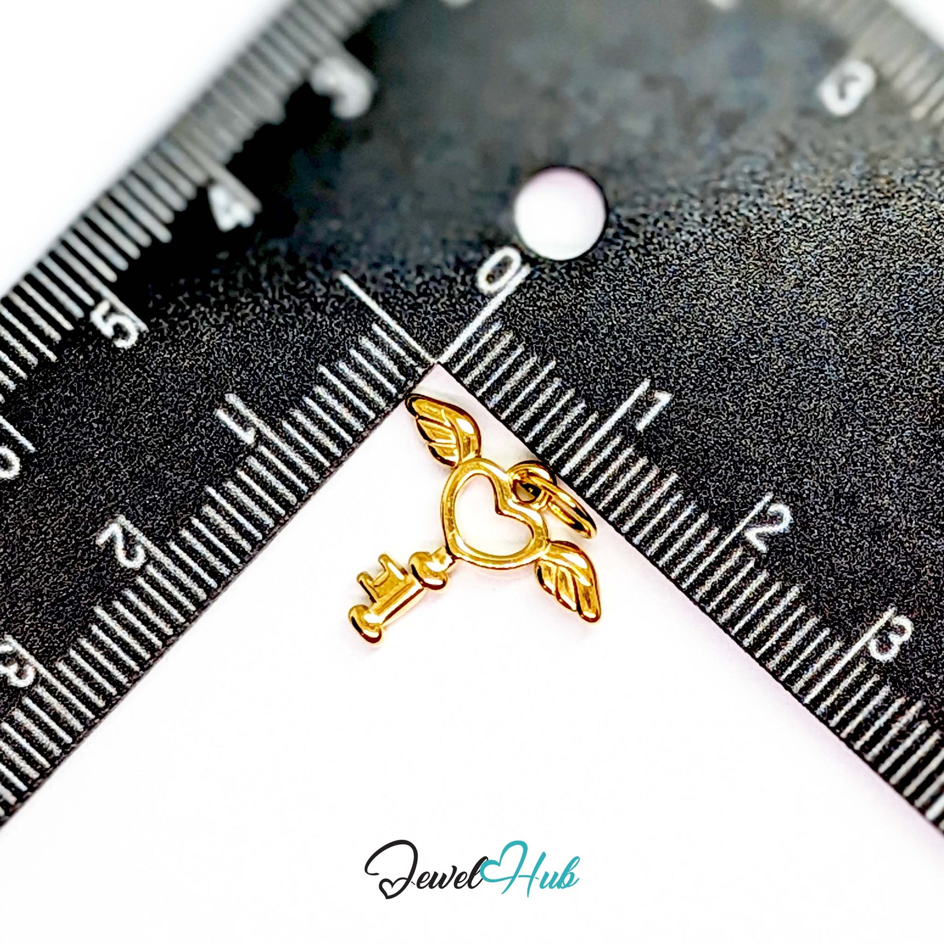 Winged heart key charm in gold stainless steel - beside a ruler for scale - JewelHub