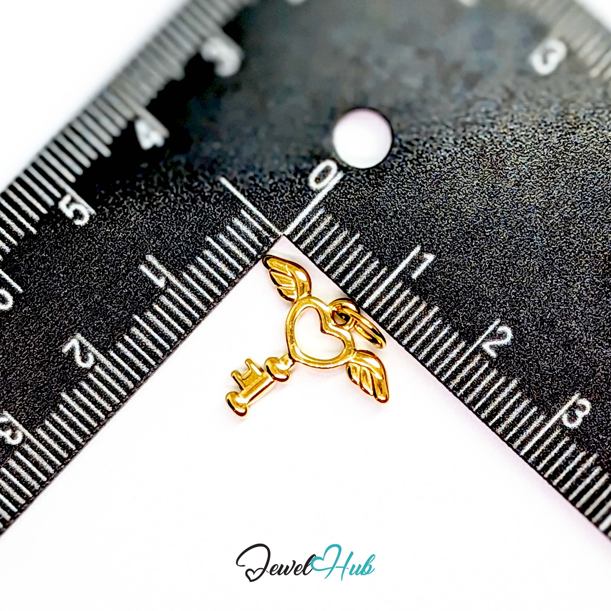 Winged heart key charm in gold stainless steel - beside a ruler for scale - JewelHub