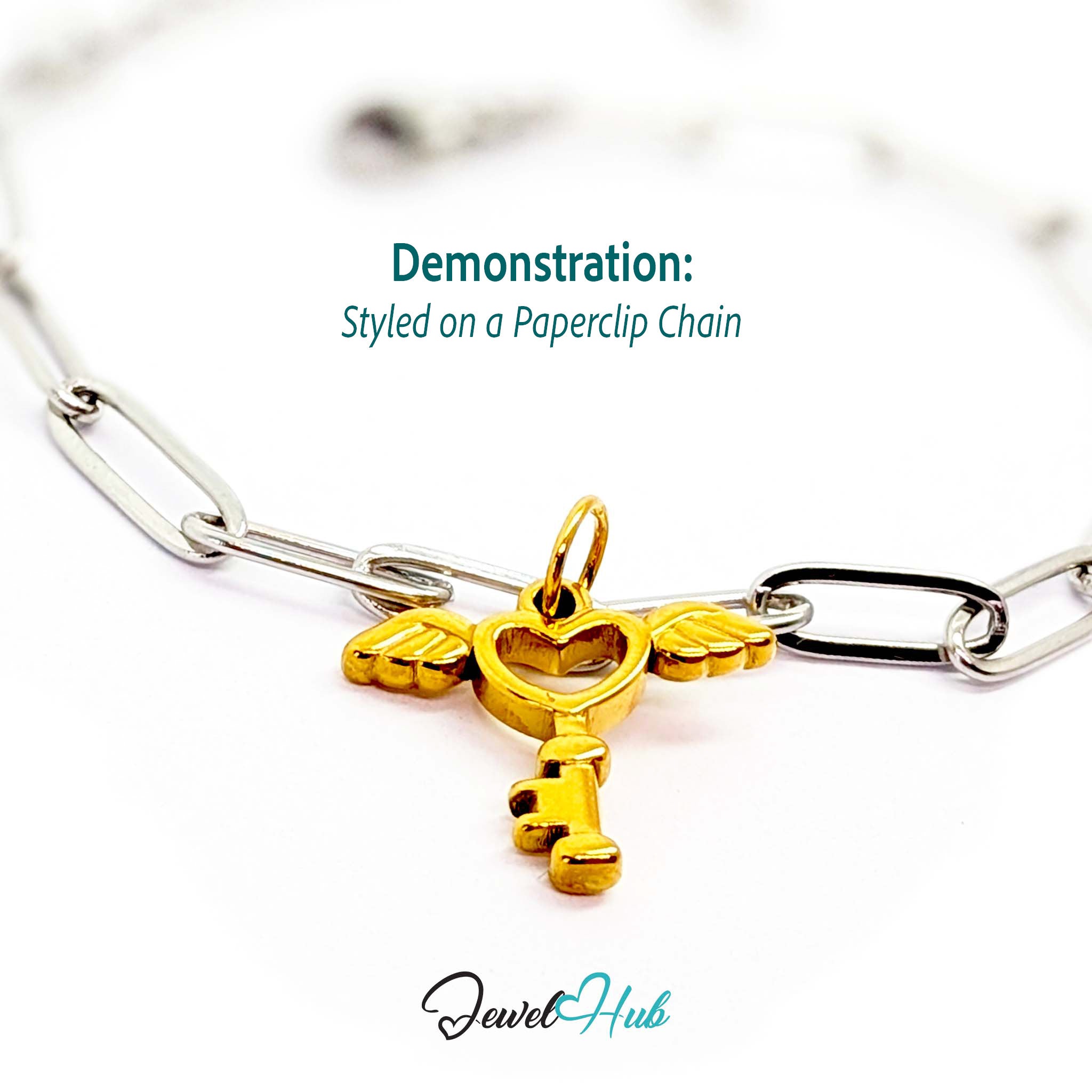 Winged heart key charm in gold stainless steel - styled on a silver paperclip chain bracelet - JewelHub
