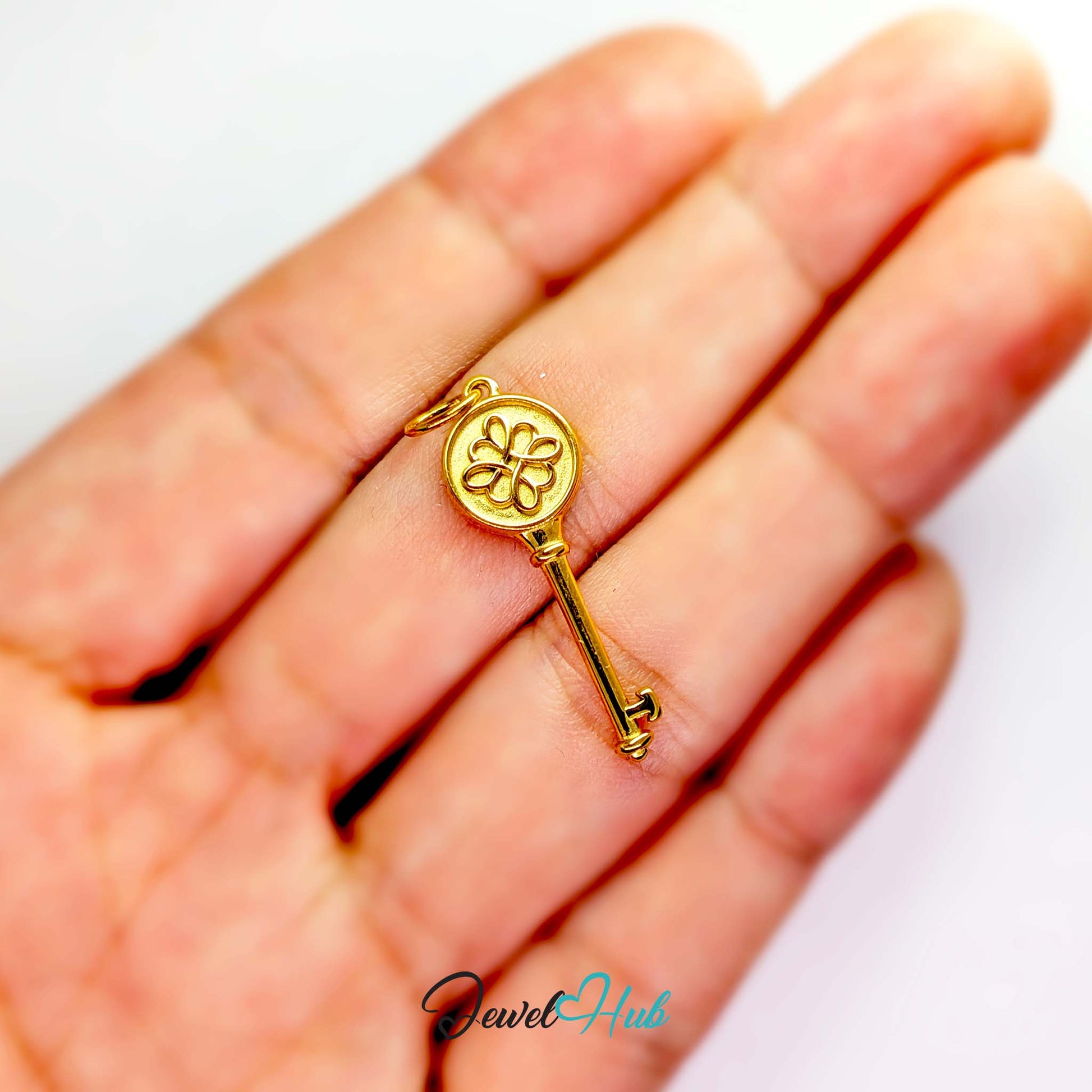 Round openwork key charm in gold stainless steel - held in the hand for scale - JewelHub