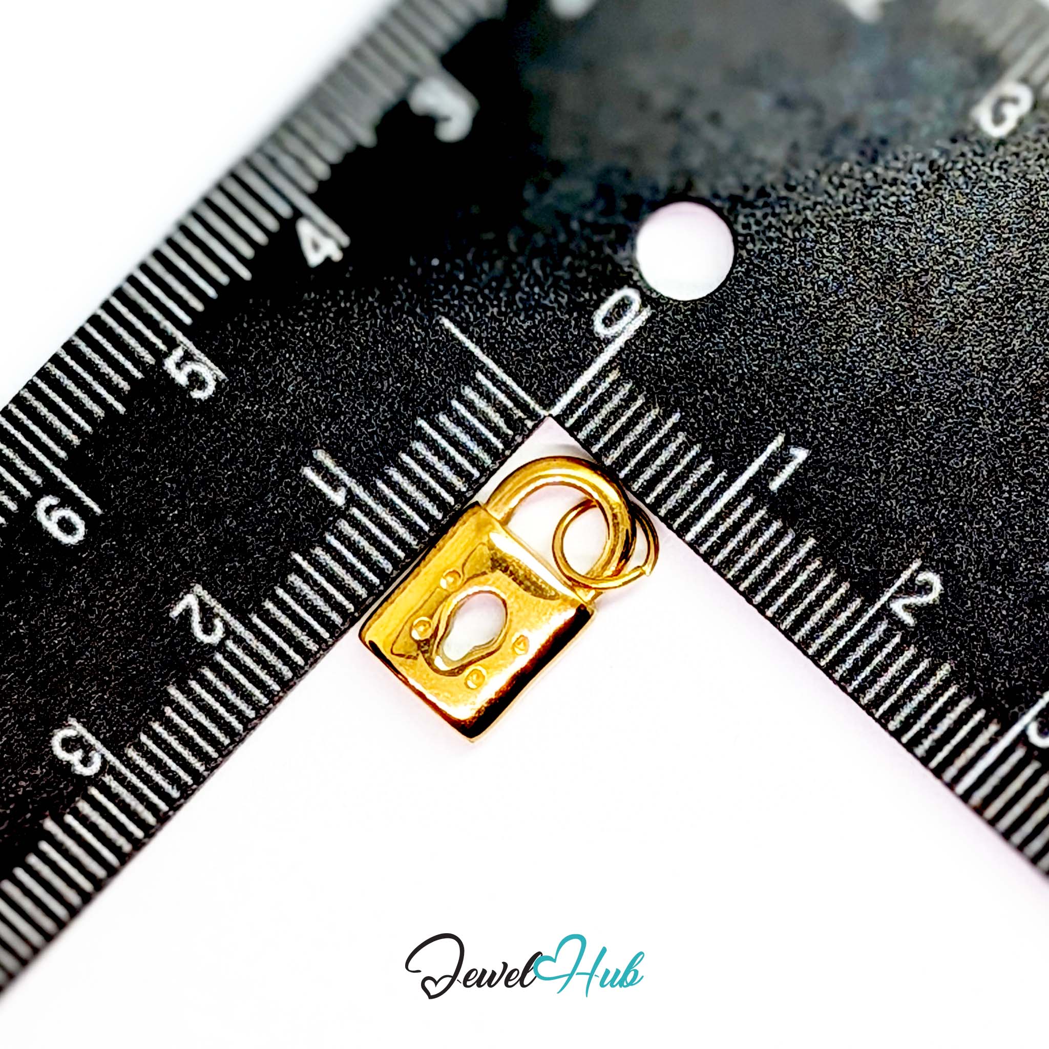 Classic padlock charm in gold stainless steel - beside a ruler for scale - JewelHub