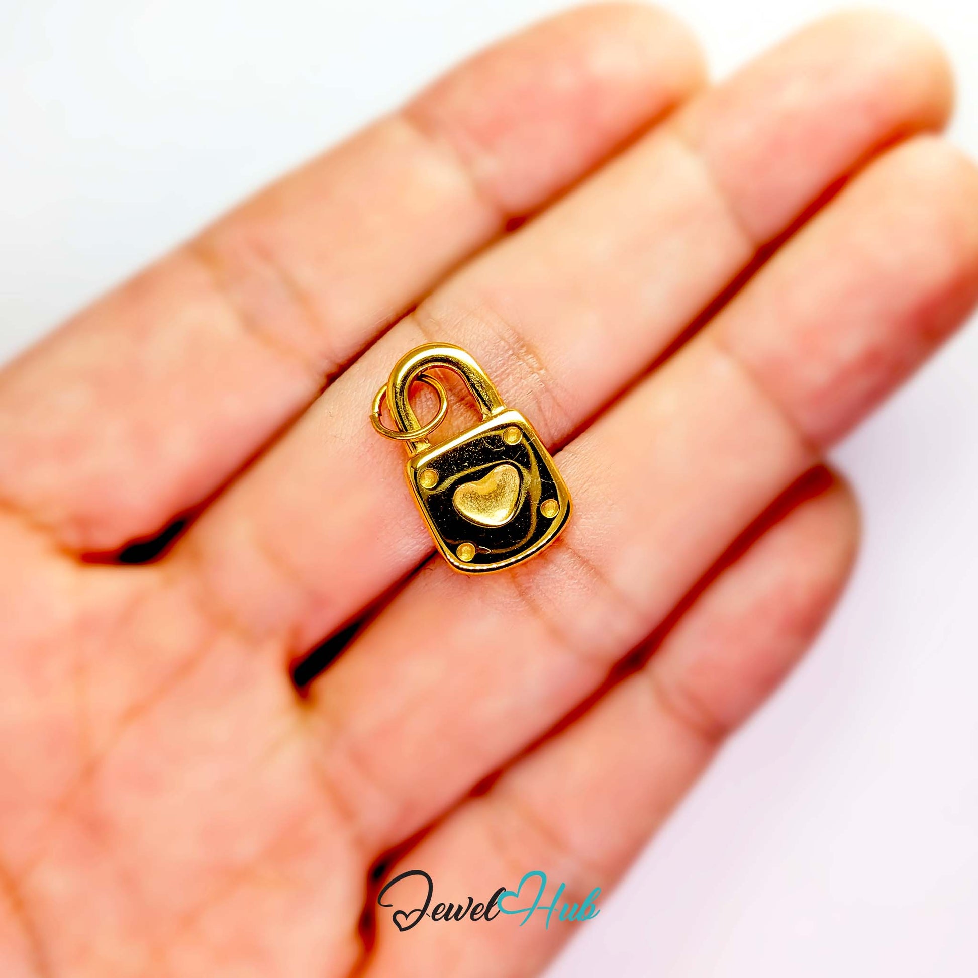 Heart padlock charm in gold stainless steel - held in the hand for scale - JewelHub