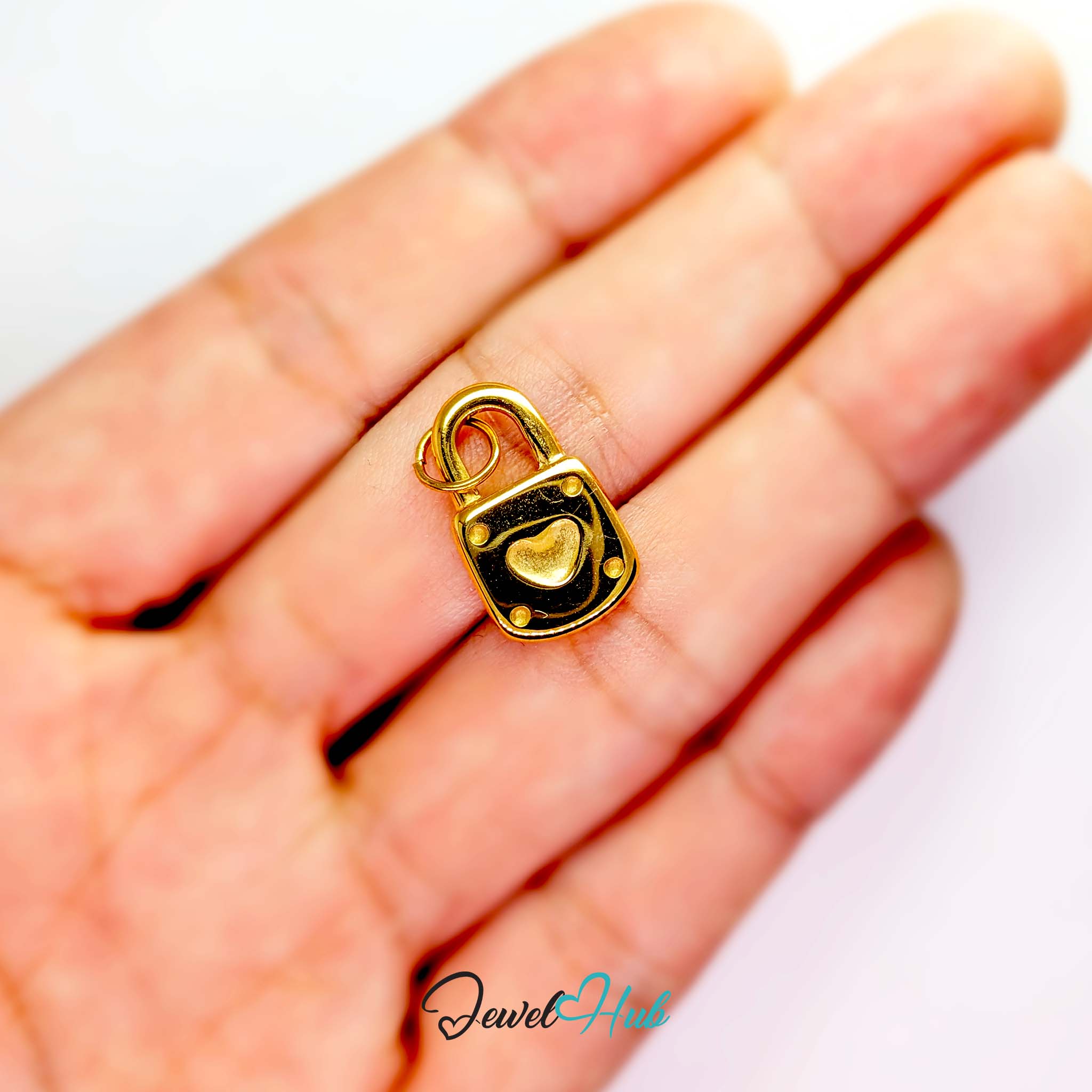 Heart padlock charm in gold stainless steel - held in the hand for scale - JewelHub