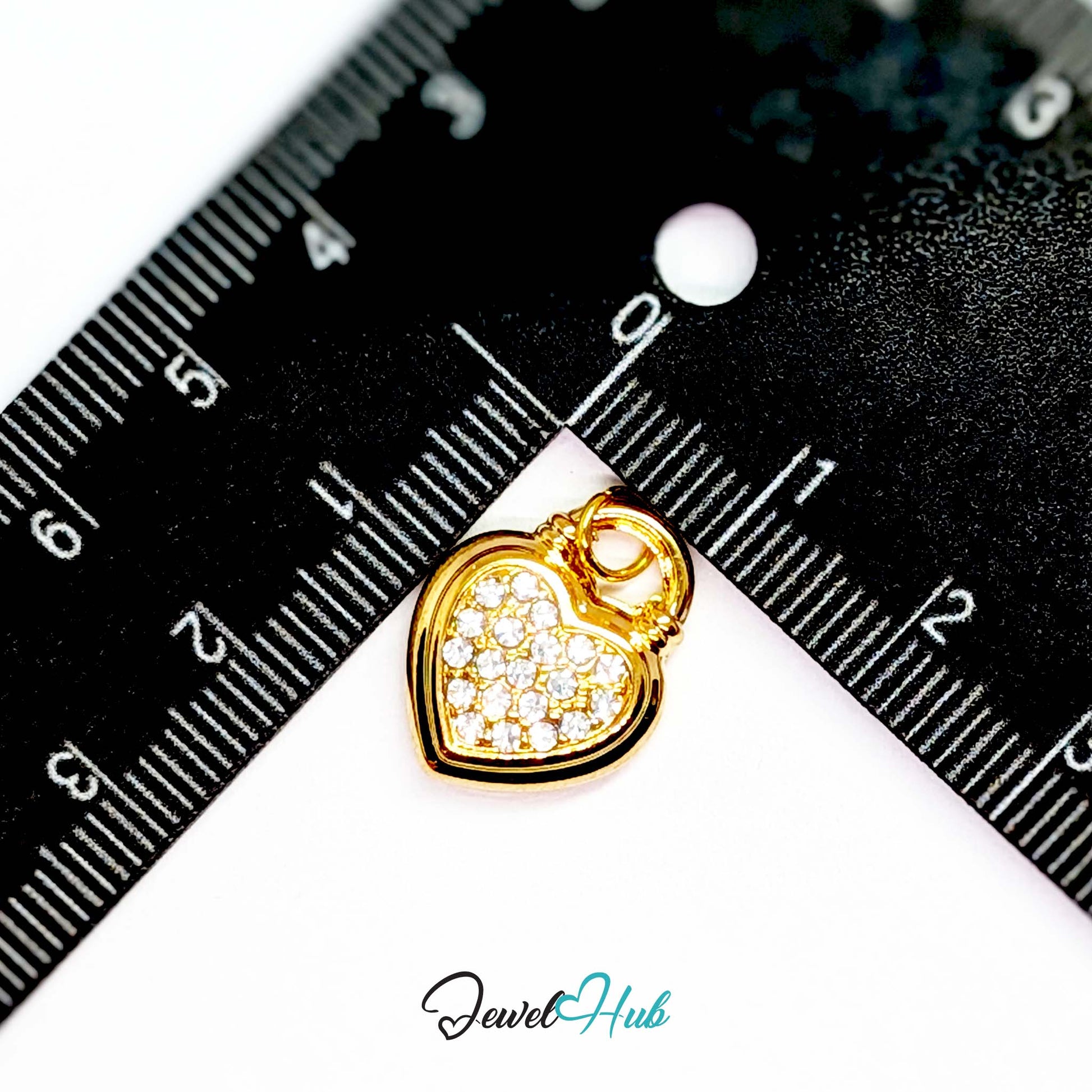 Pave heart padlock charm in gold stainless steel - beside a ruler for scale - JewelHub