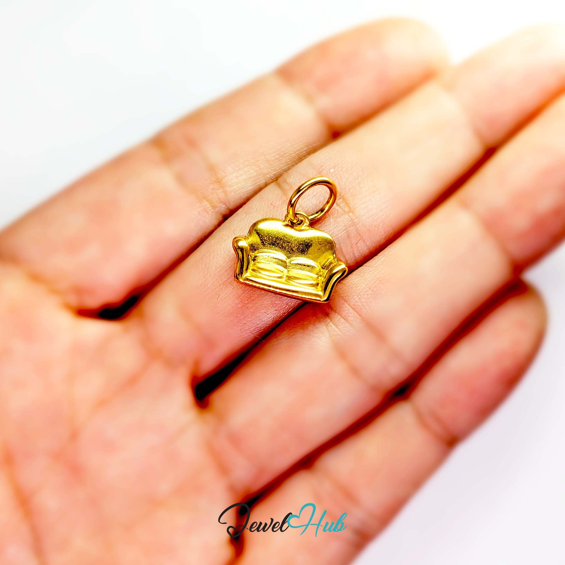 Three-dimensional sofa charm in gold stainless steel - held in the hand for scale - JewelHub