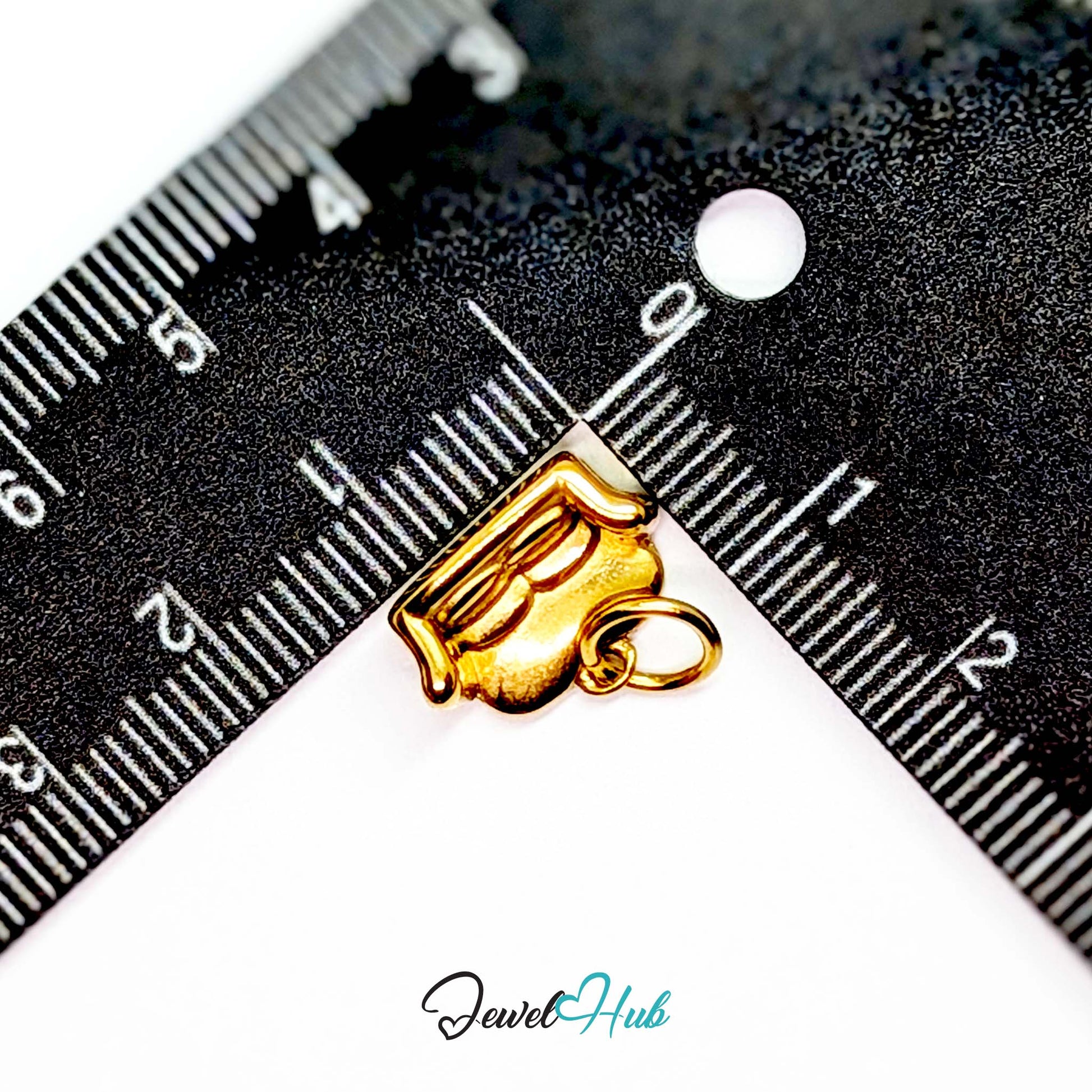 Three-dimensional sofa charm in gold stainless steel - beside a ruler for scale - JewelHub