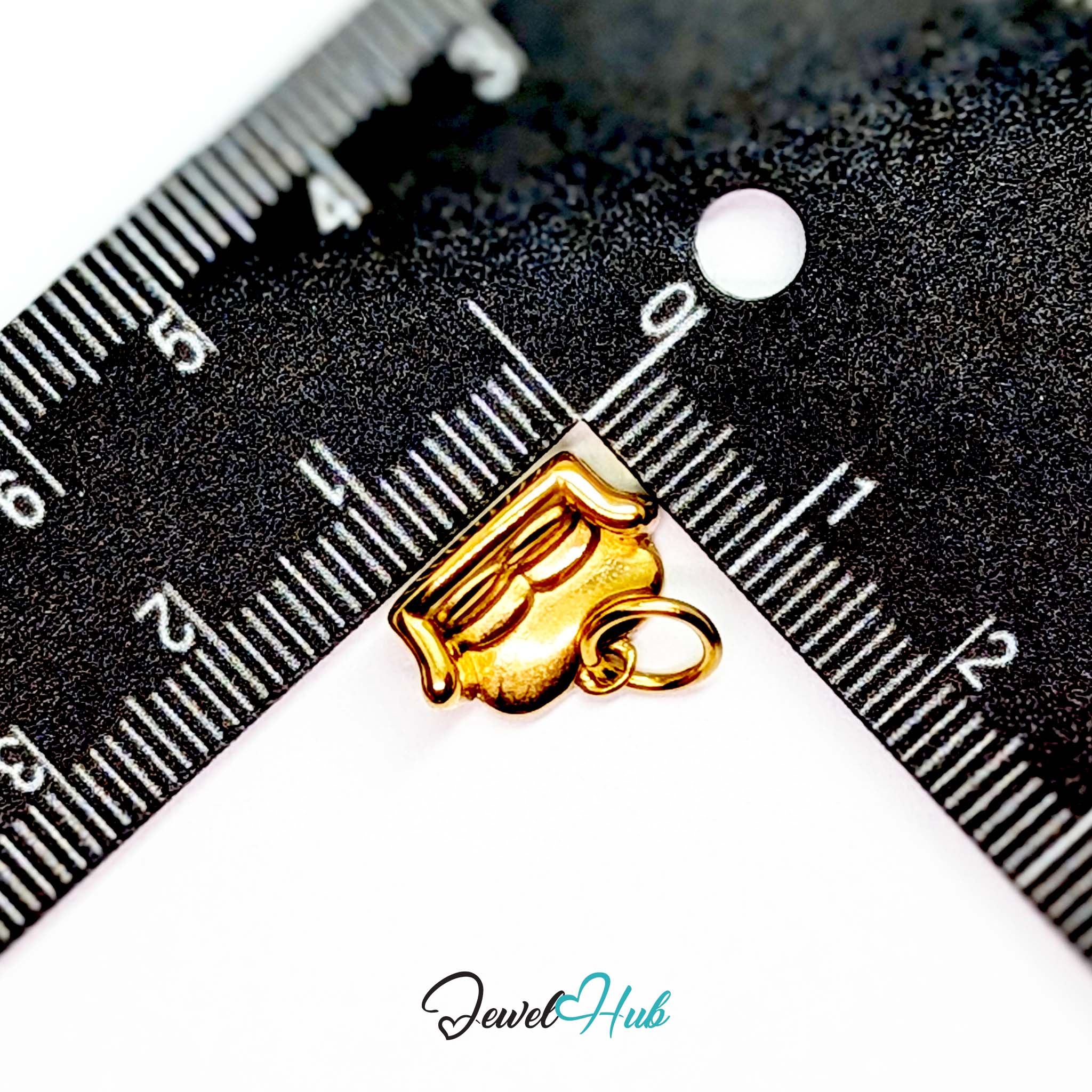 Three-dimensional sofa charm in gold stainless steel - beside a ruler for scale - JewelHub