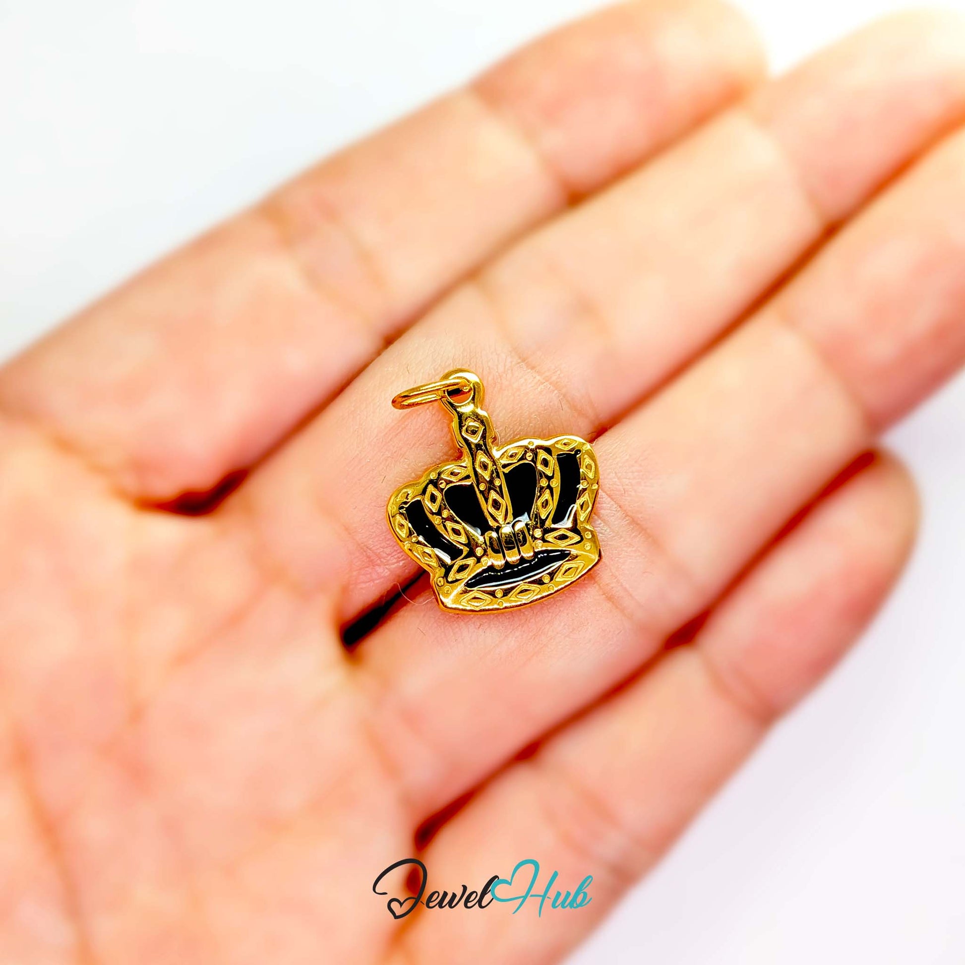 Crown charm in gold stainless steel with black enamel - held in the hand for scale - JewelHub
