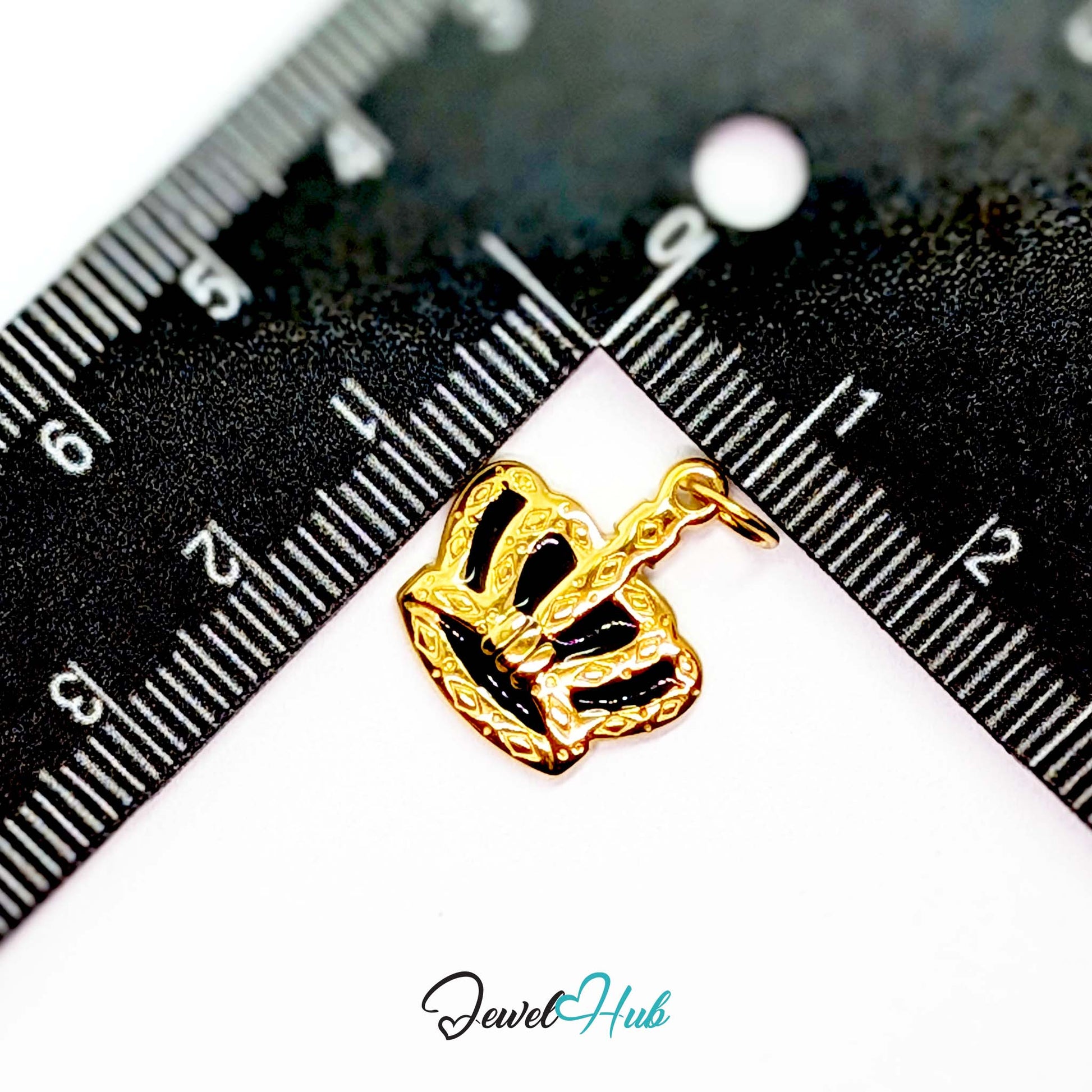 Crown charm in gold stainless steel with black enamel - beside a ruler for scale - JewelHub