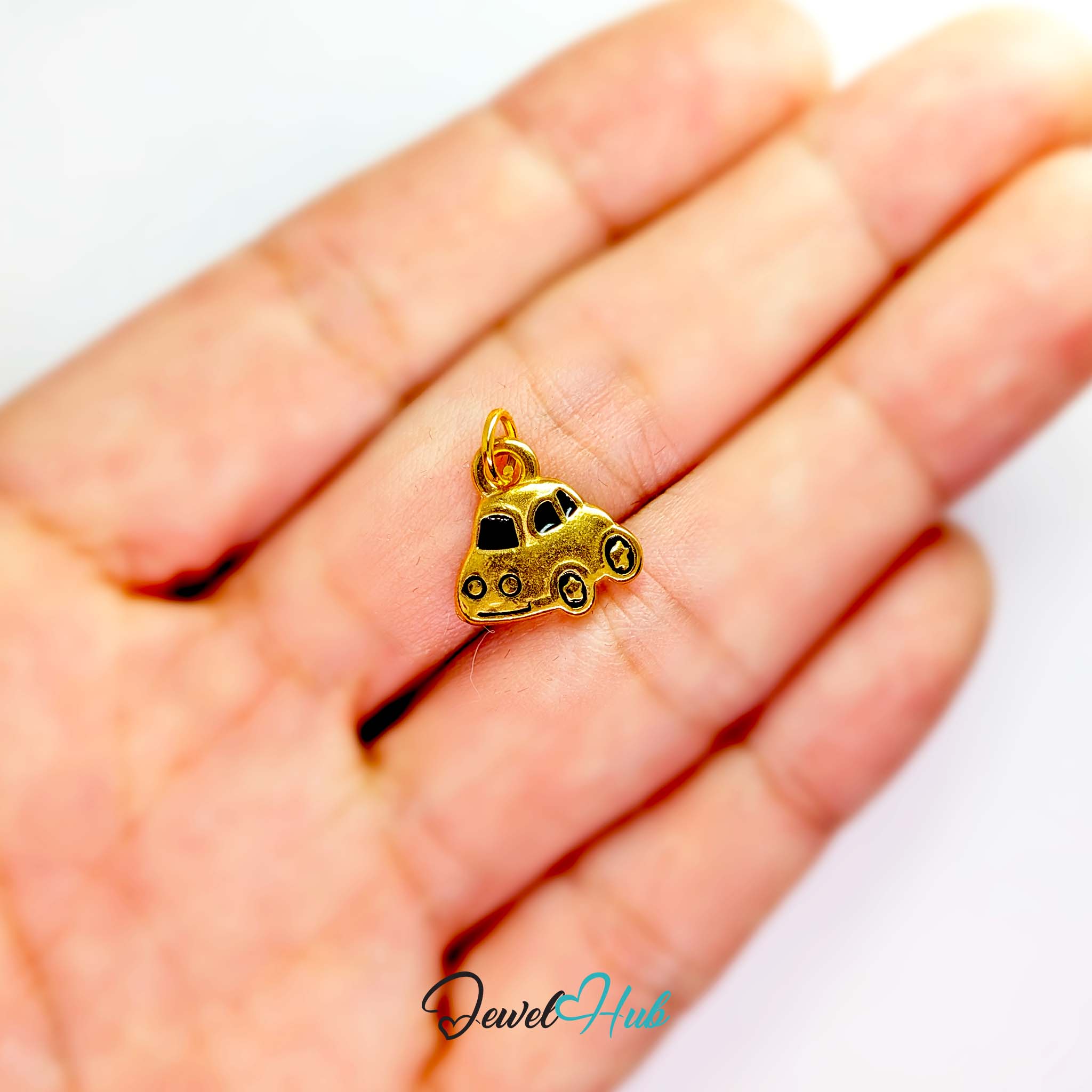 Little car charm in gold stainless steel with black enamel - held in the hand for scale - JewelHub