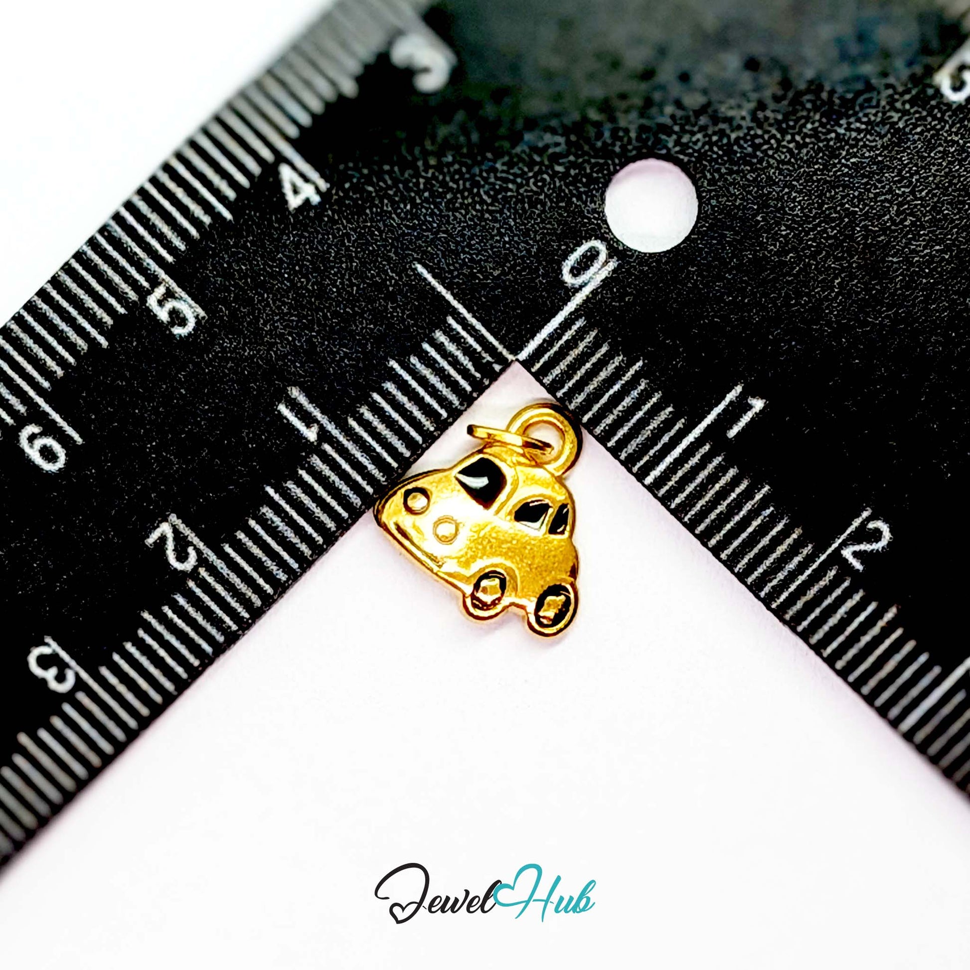 Little car charm in gold stainless steel with black enamel - beside a ruler for scale - JewelHub