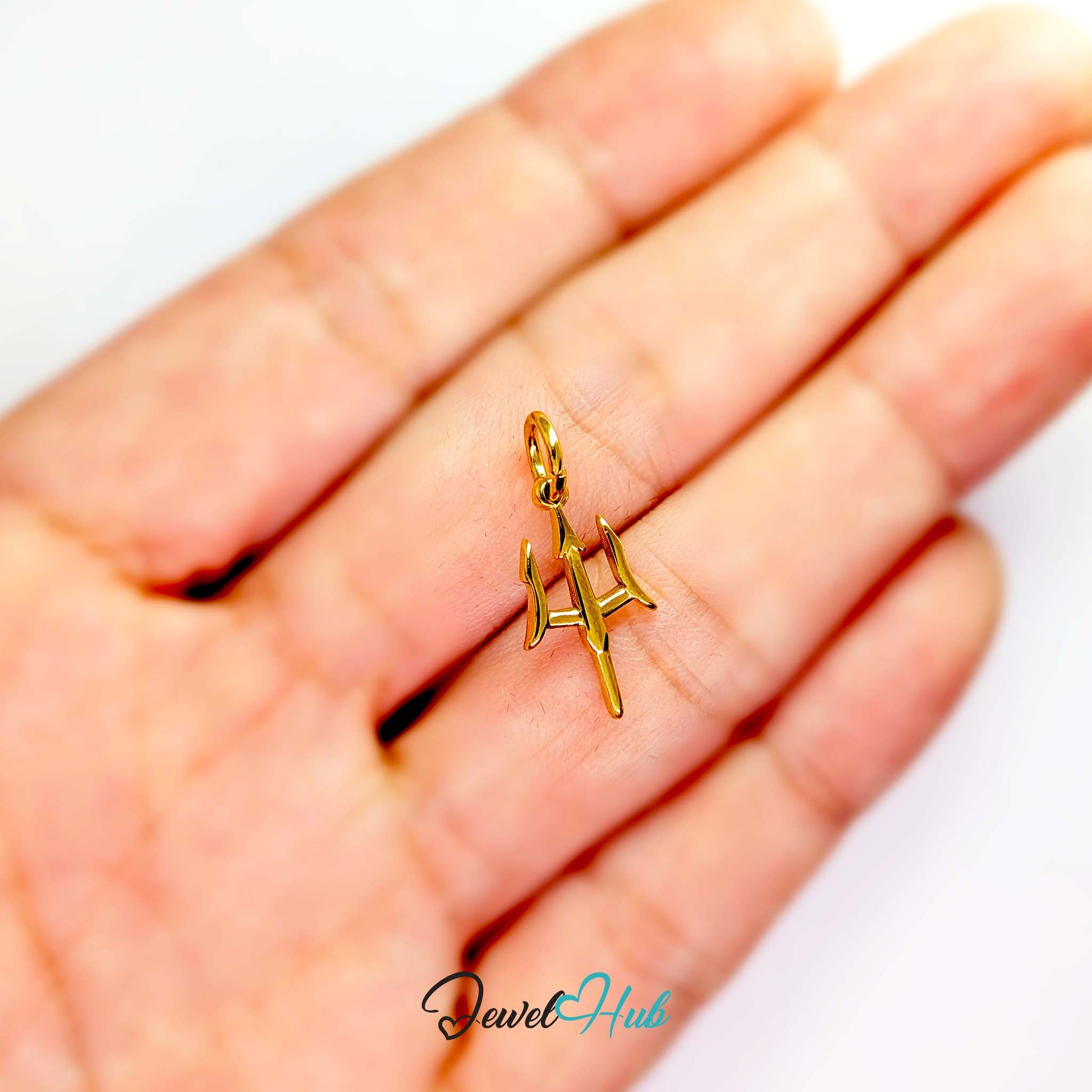 Trident charm in gold stainless steel - held in the hand for scale - JewelHub