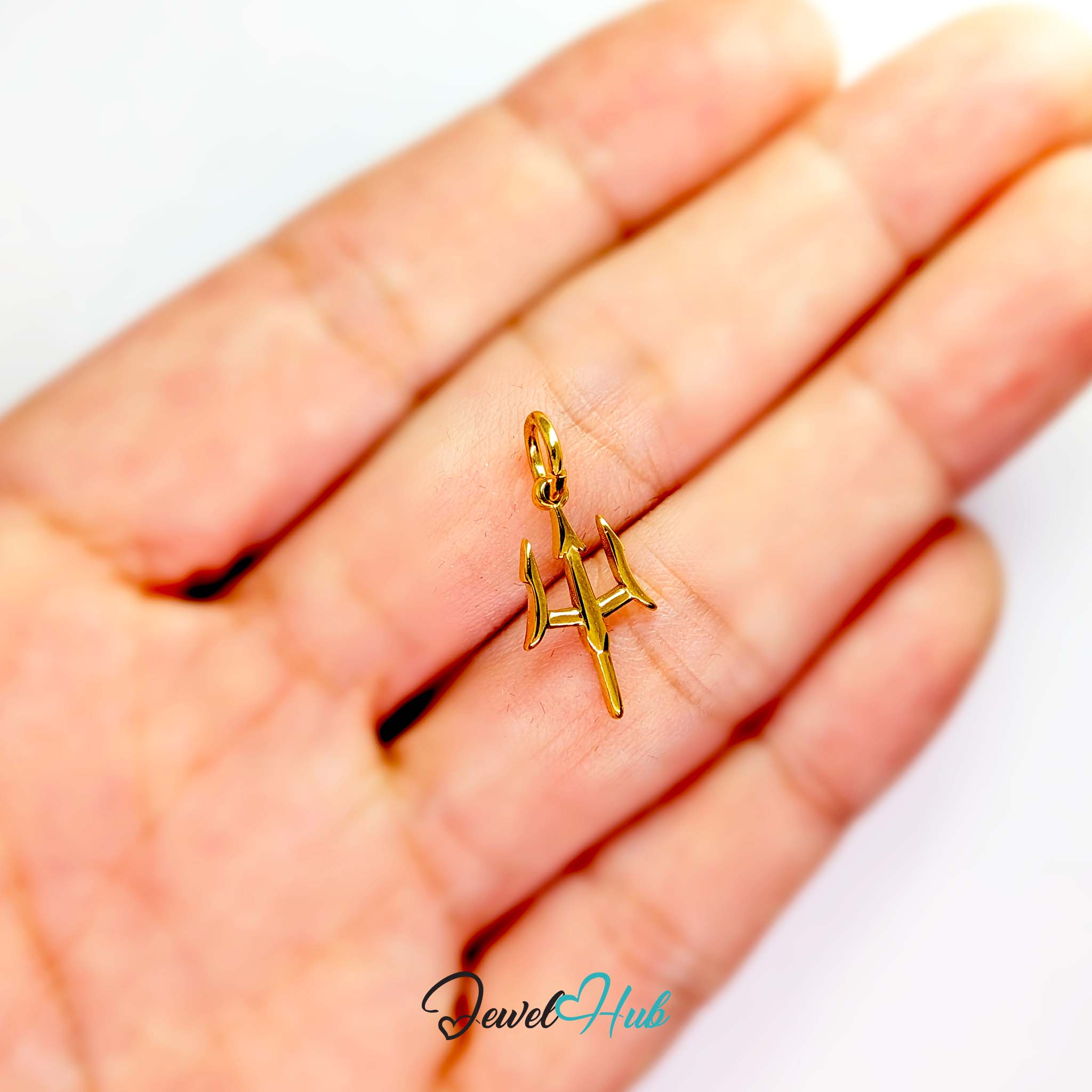Trident charm in gold stainless steel - held in the hand for scale - JewelHub