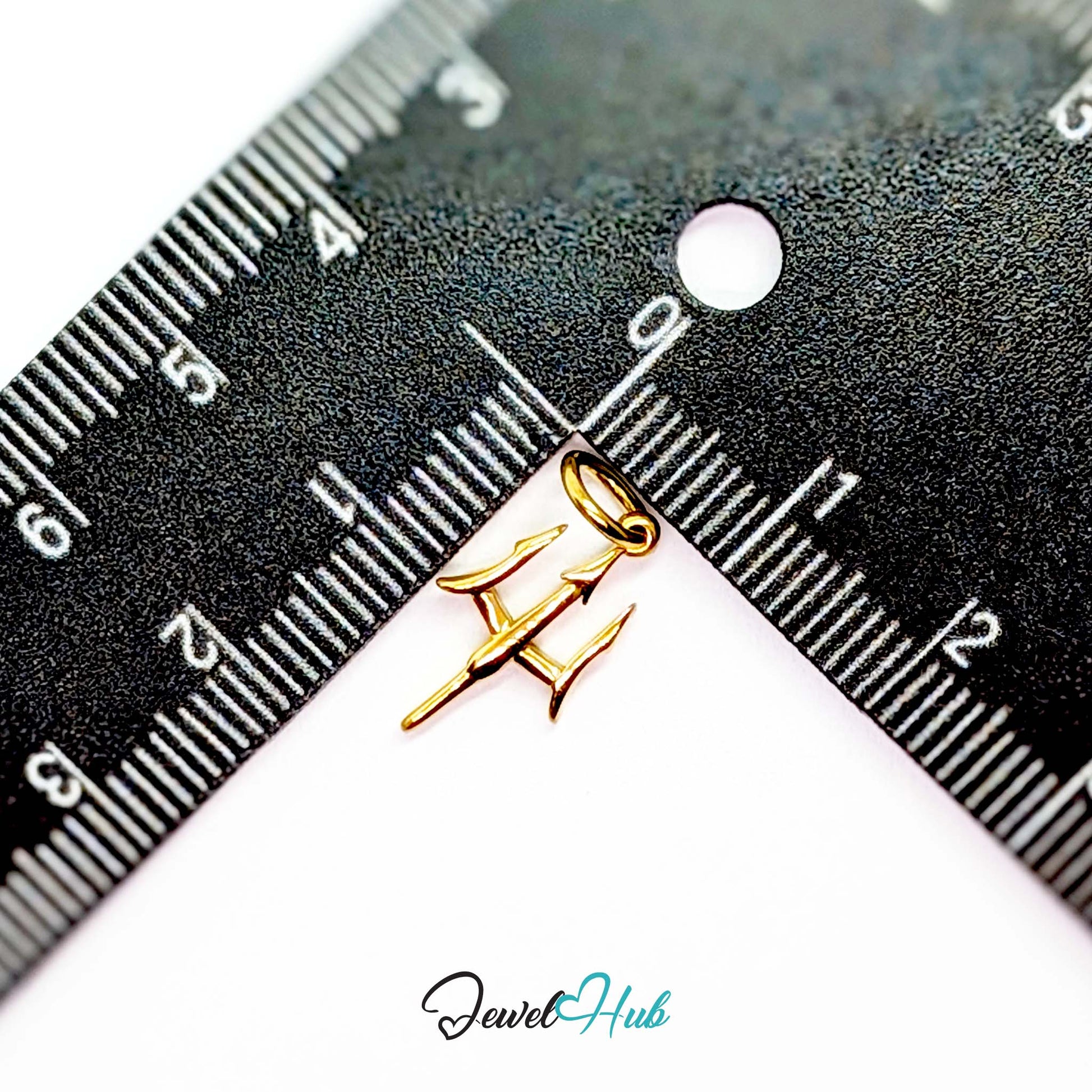 Trident charm in gold stainless steel - beside a ruler for scale - JewelHub