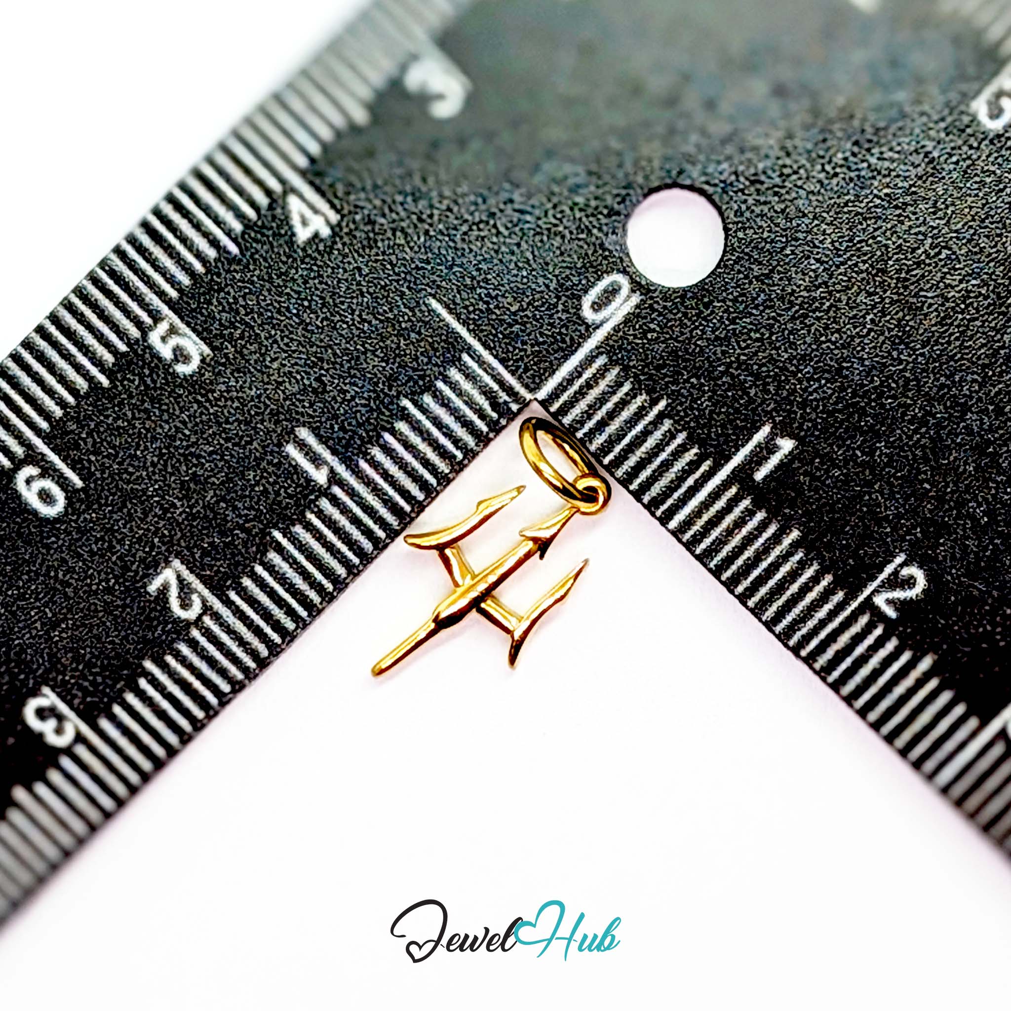 Trident charm in gold stainless steel - beside a ruler for scale - JewelHub