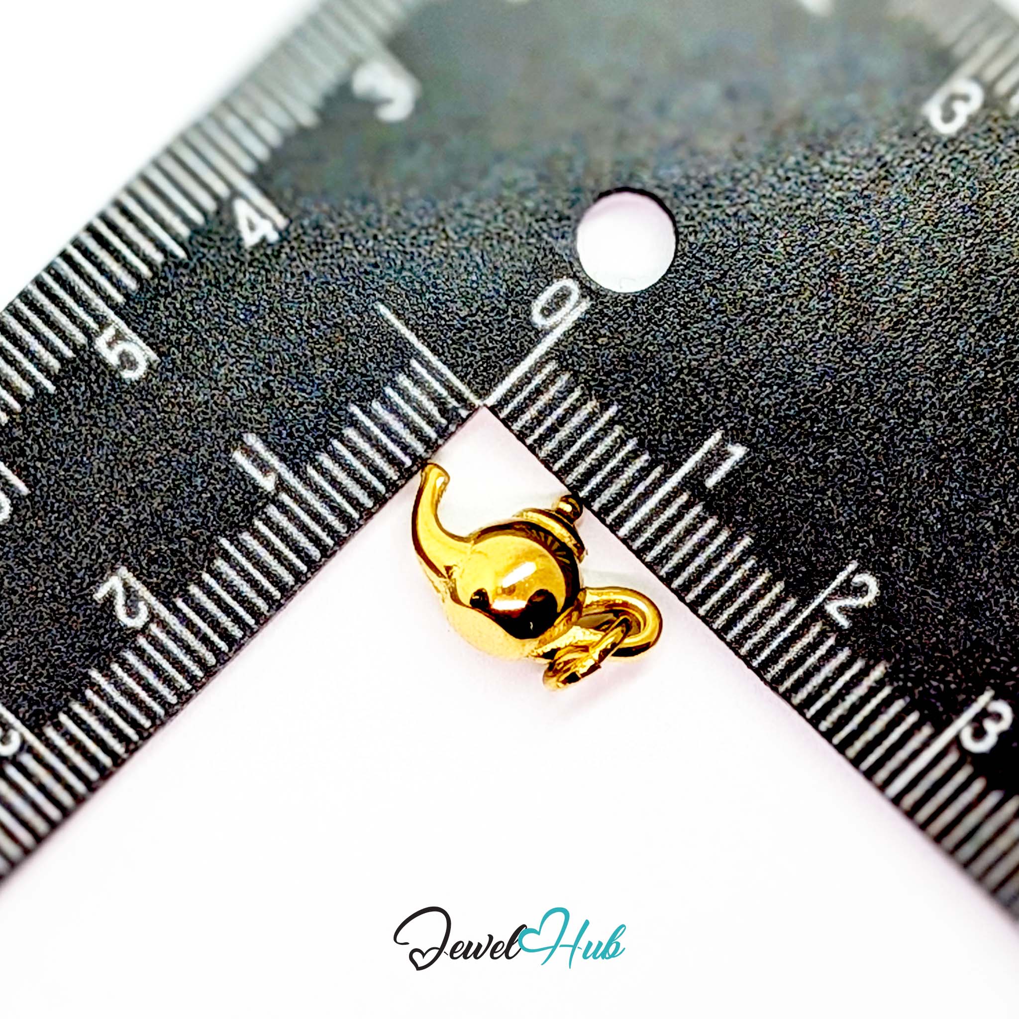 Three-dimensional teapot charm in gold stainless steel - beside a ruler for scale - JewelHub