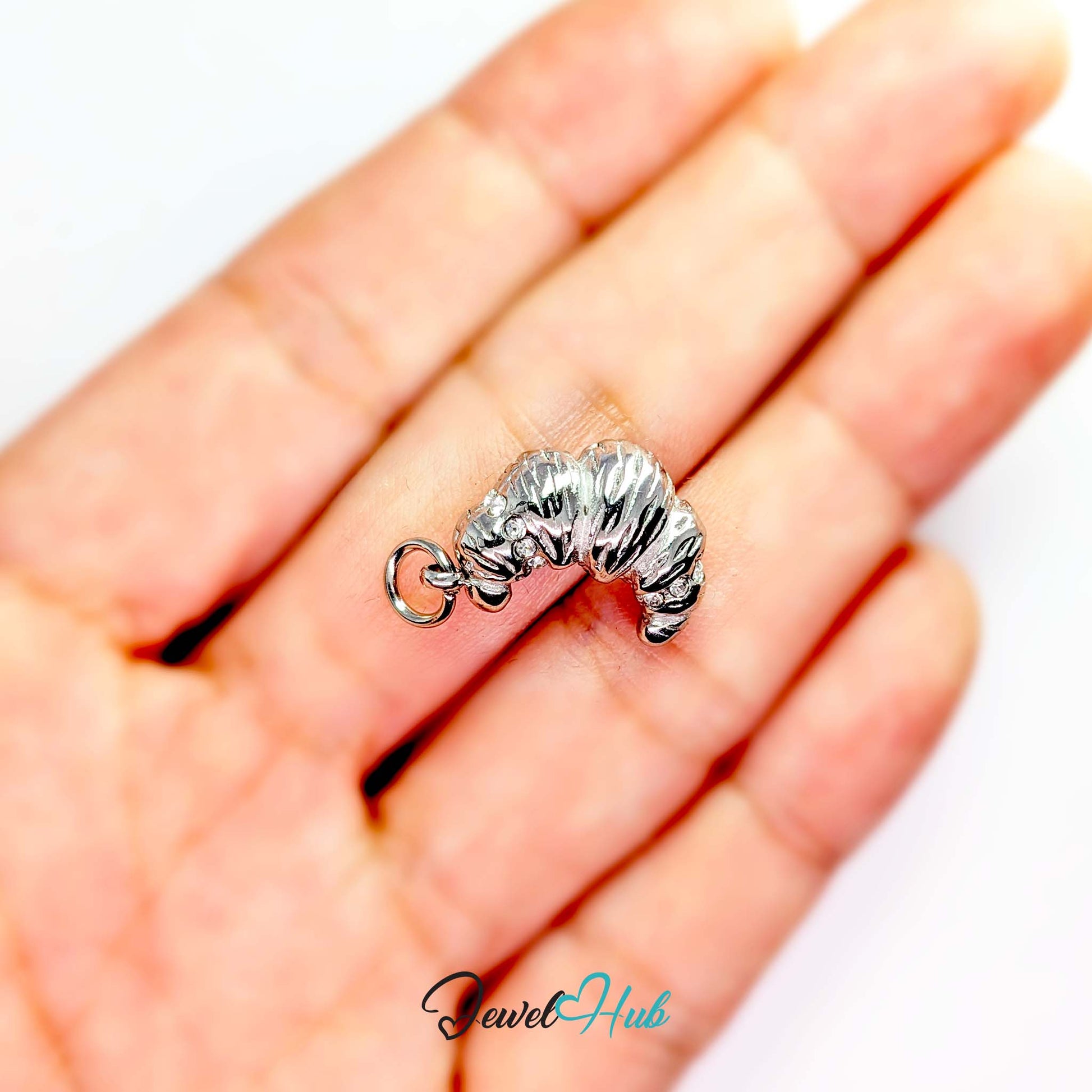 Croissant charm in silver stainless steel with clear crystals - held in the hand for scale - JewelHub