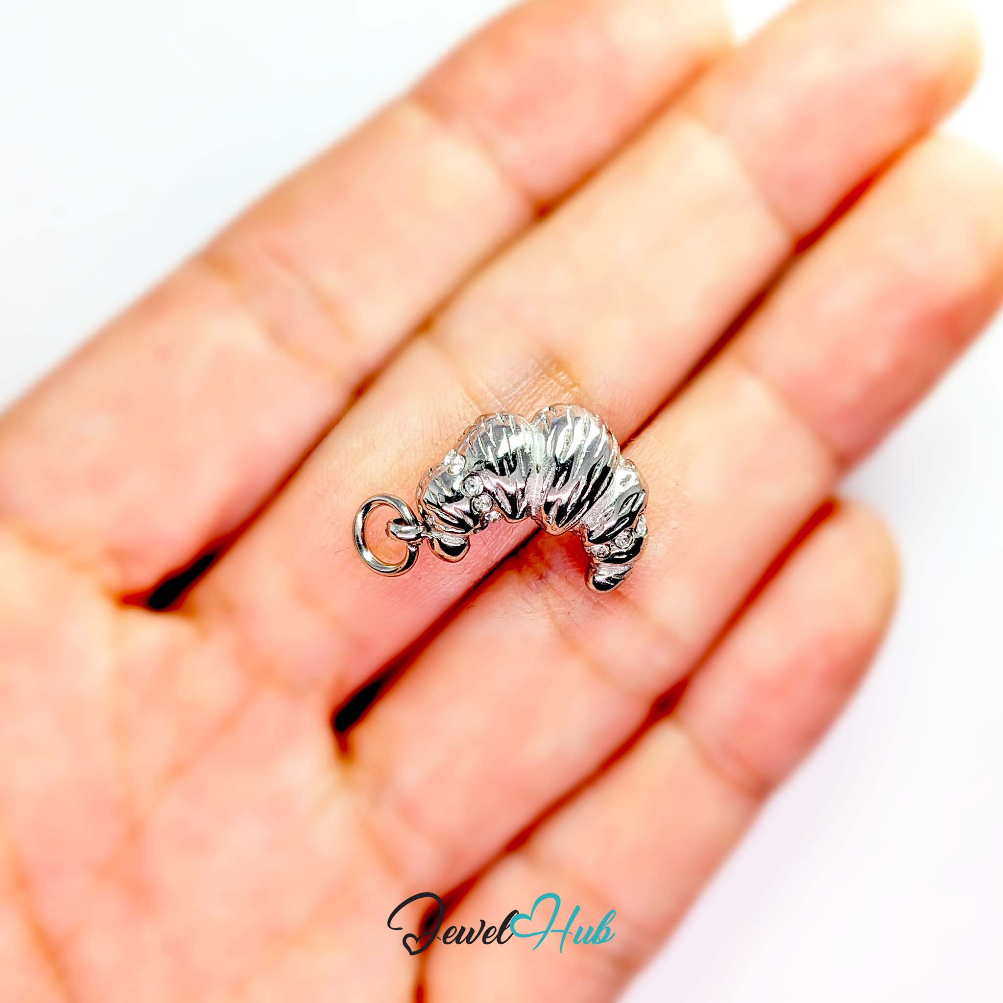 Croissant charm in silver stainless steel with clear crystals - held in the hand for scale - JewelHub