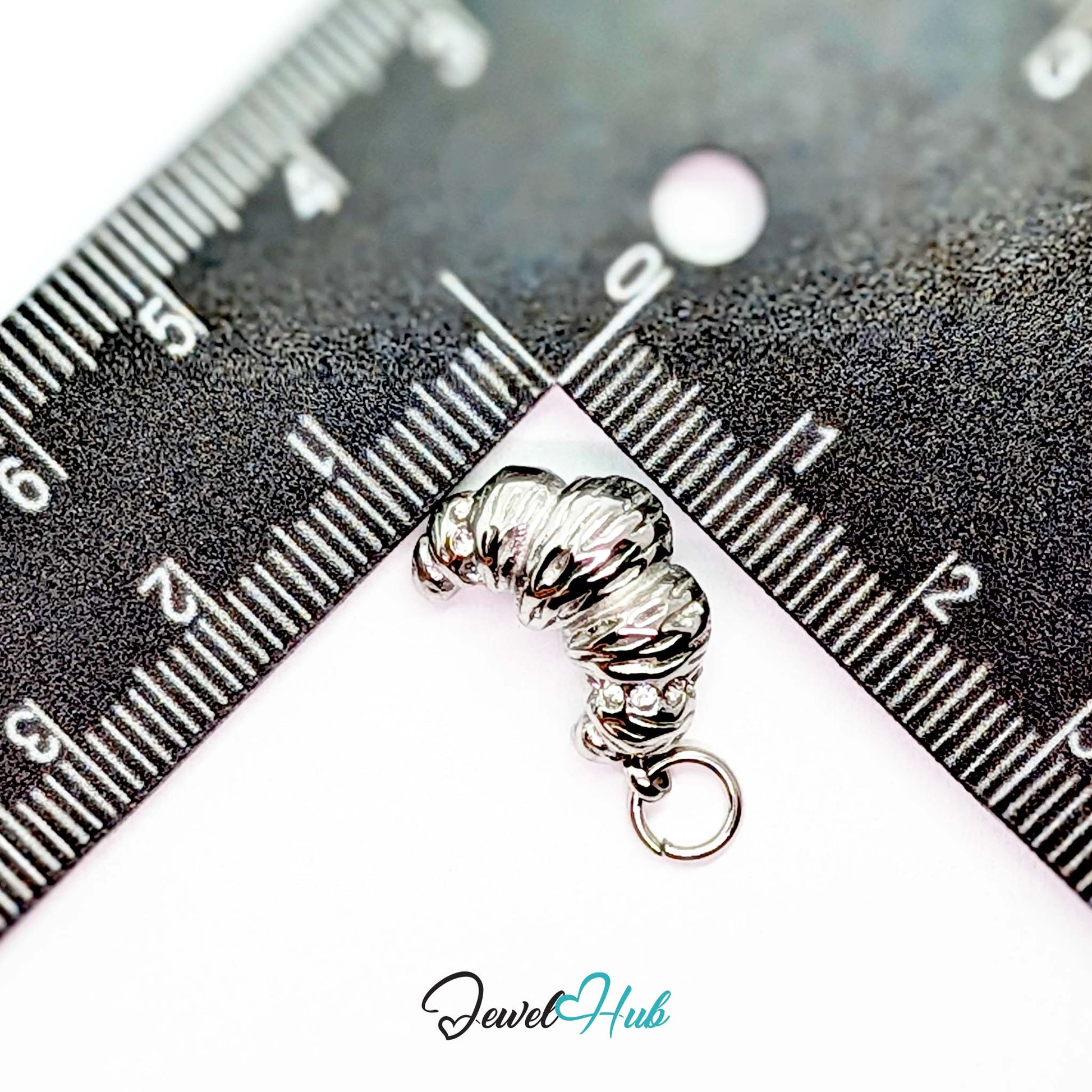 Croissant charm in silver stainless steel with clear crystals - beside a ruler for scale - JewelHub