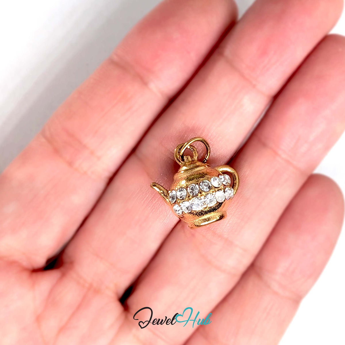 Crystal teapot charm held in a hand to show its size - JewelHub