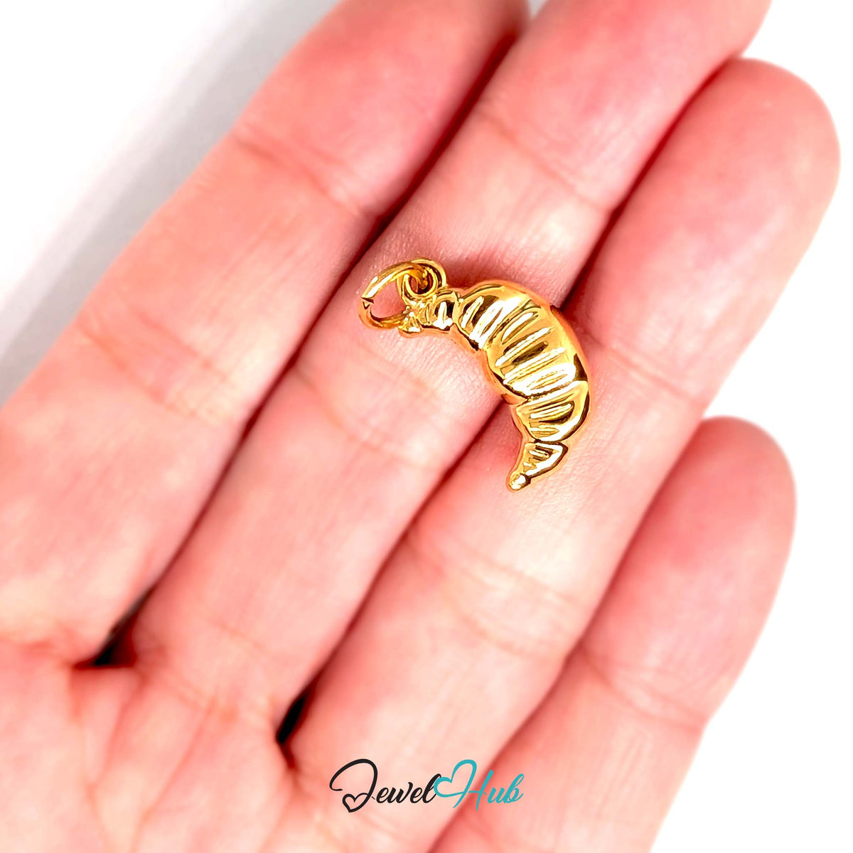 Slim ridged croissant charm held in a hand to show its size - JewelHub