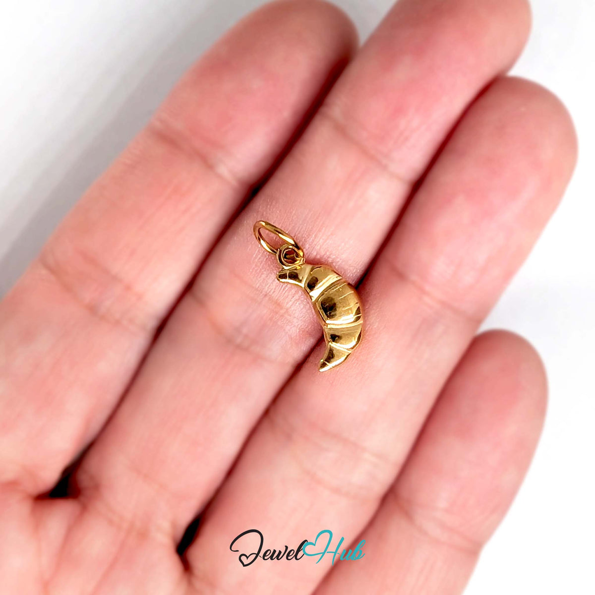 Mini croissant charm held in a hand to show its size - JewelHub