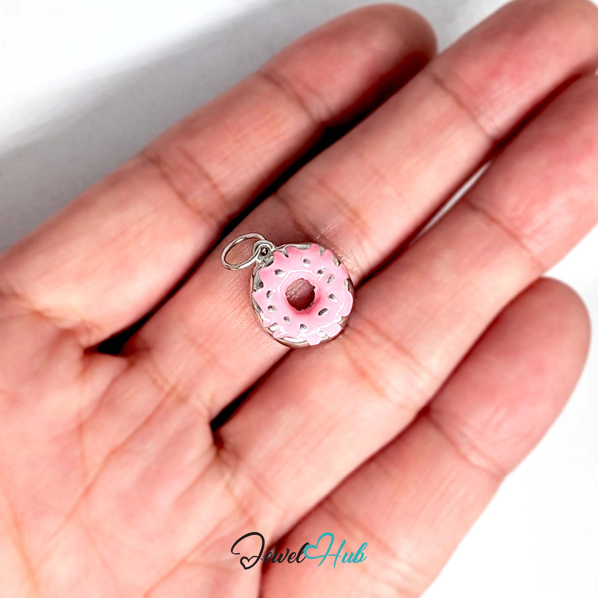 Pink sprinkle donut charm held in a hand to show its size - JewelHub