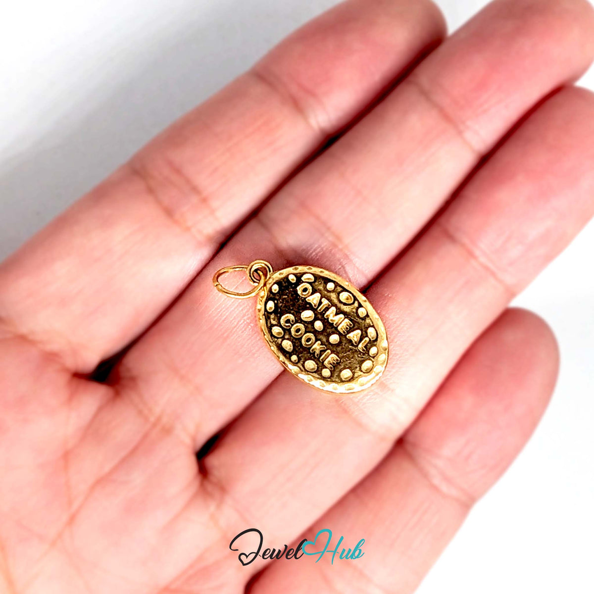 Oatmeal cookie charm held in a hand to show its size - JewelHub