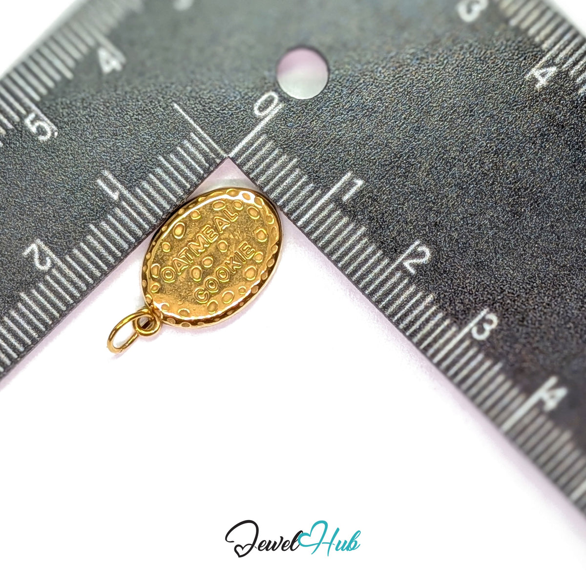 Oatmeal cookie charm measured against a ruler at 12.5mm wide by 19.8mm tall - JewelHub