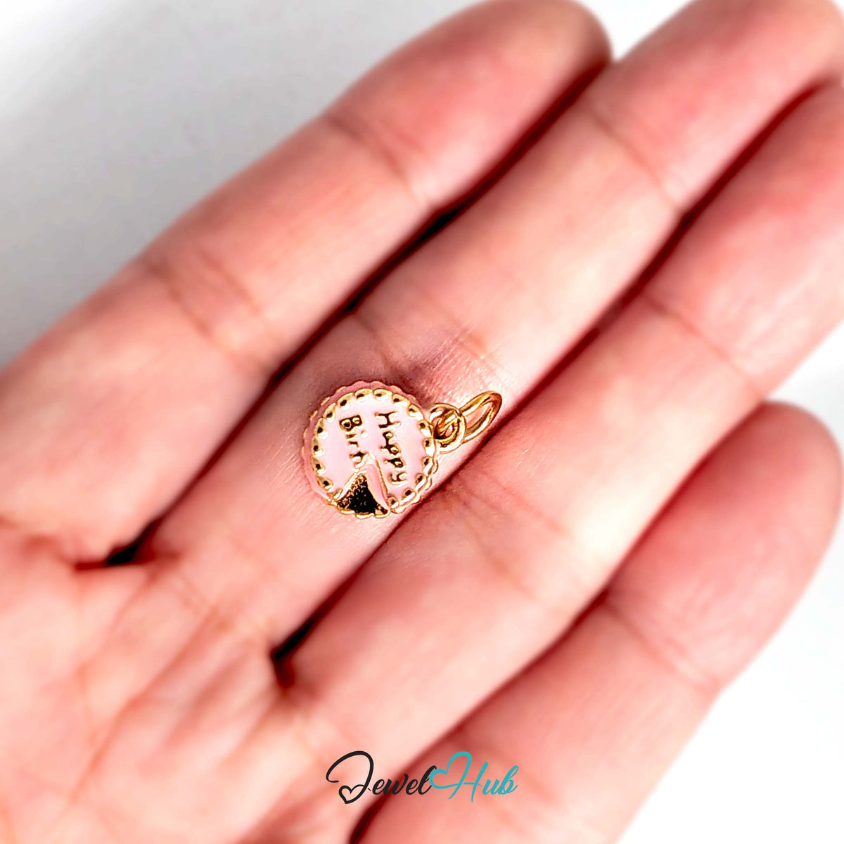 Pink birthday cake charm held in a hand to show its size - JewelHub
