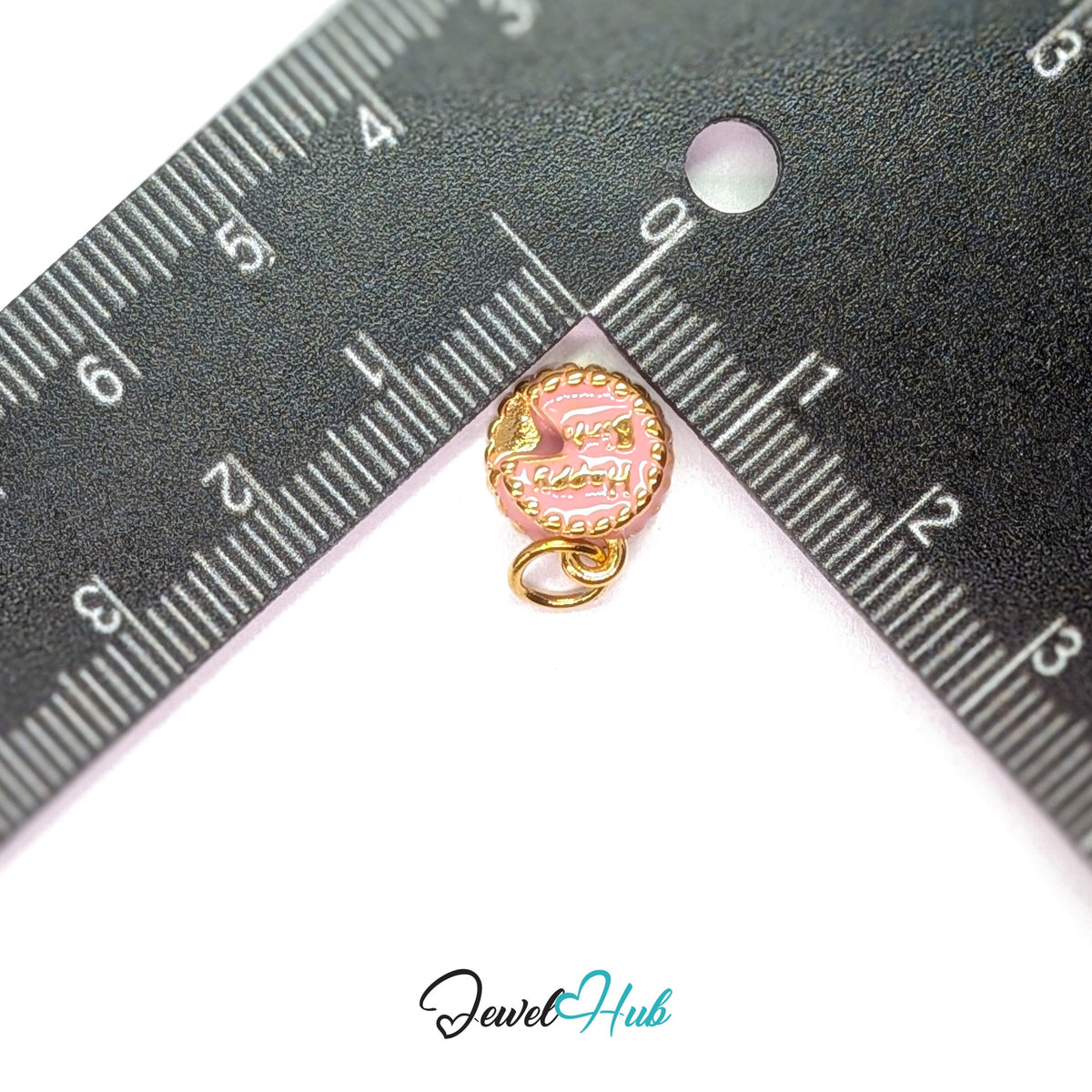 Pink birthday cake charm measured against a ruler at 10.5mm wide by 12mm tall - JewelHub