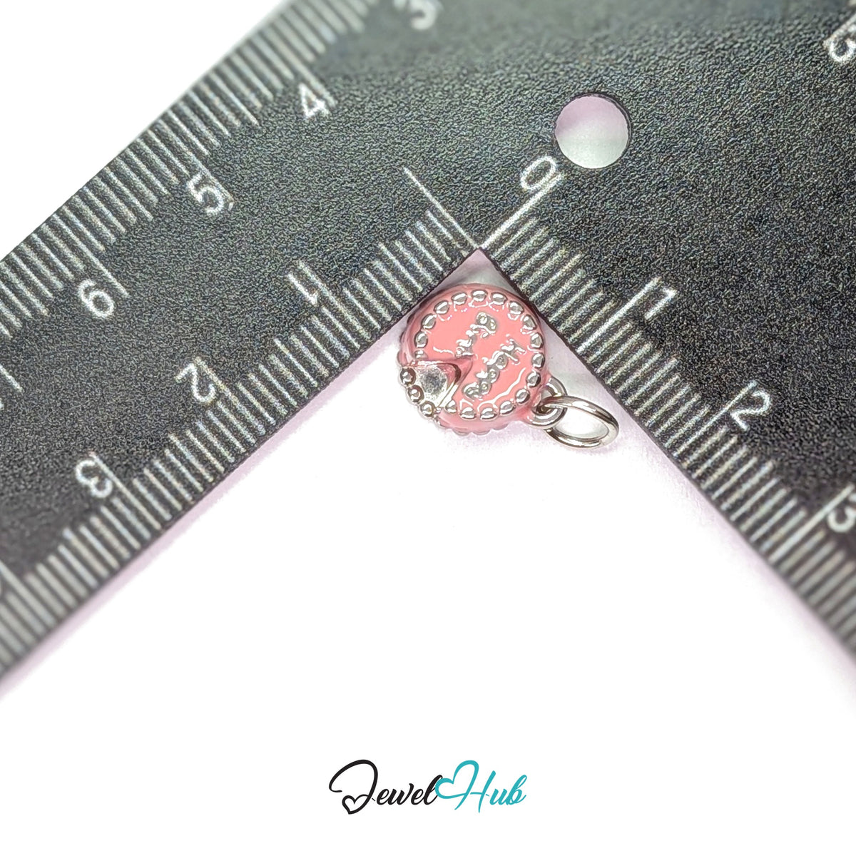Pink birthday cake charm measured against a ruler at 10.5mm wide by 12mm tall - JewelHub