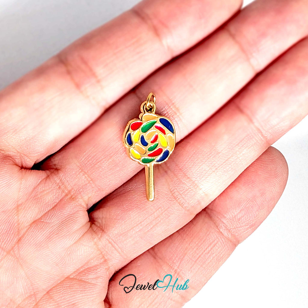 Rainbow swirl lollipop charm held in a hand to show its size - JewelHub
