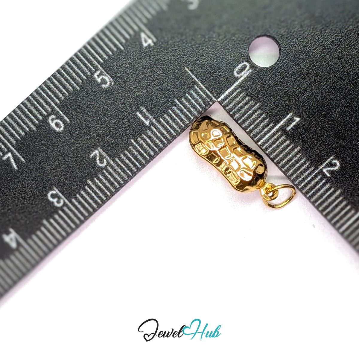Hammered peanut charm measured against a ruler at 8mm wide by 19mm tall - JewelHub