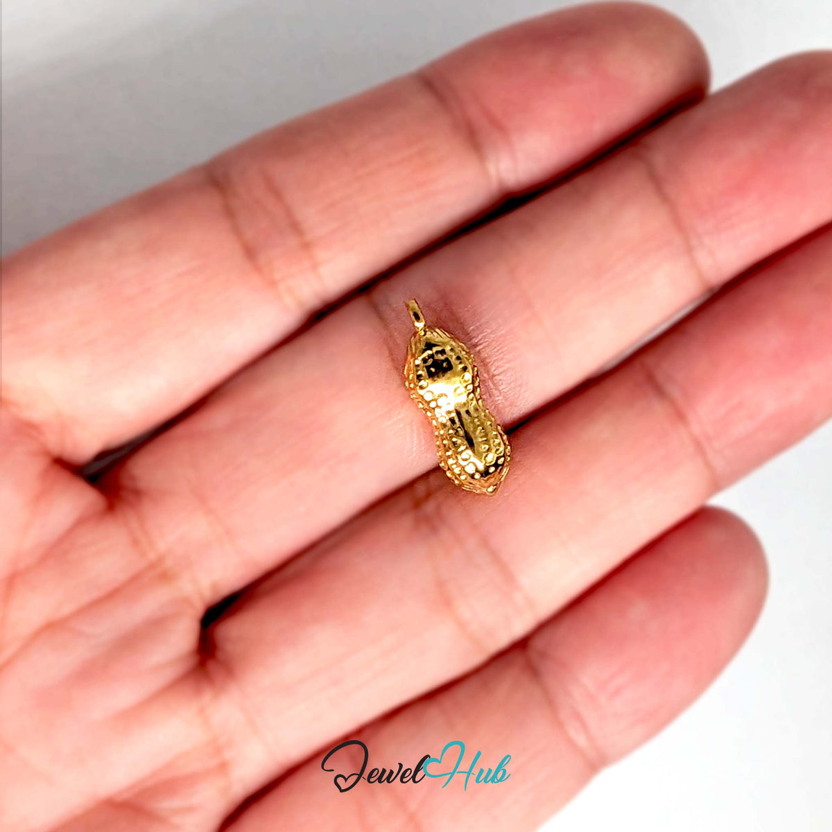 Dotted peanut charm held in a hand to show its size - JewelHub
