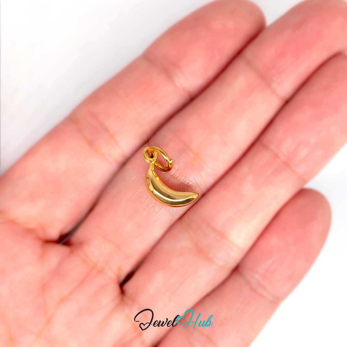 Polished banana charm held in a hand to show its size - JewelHub