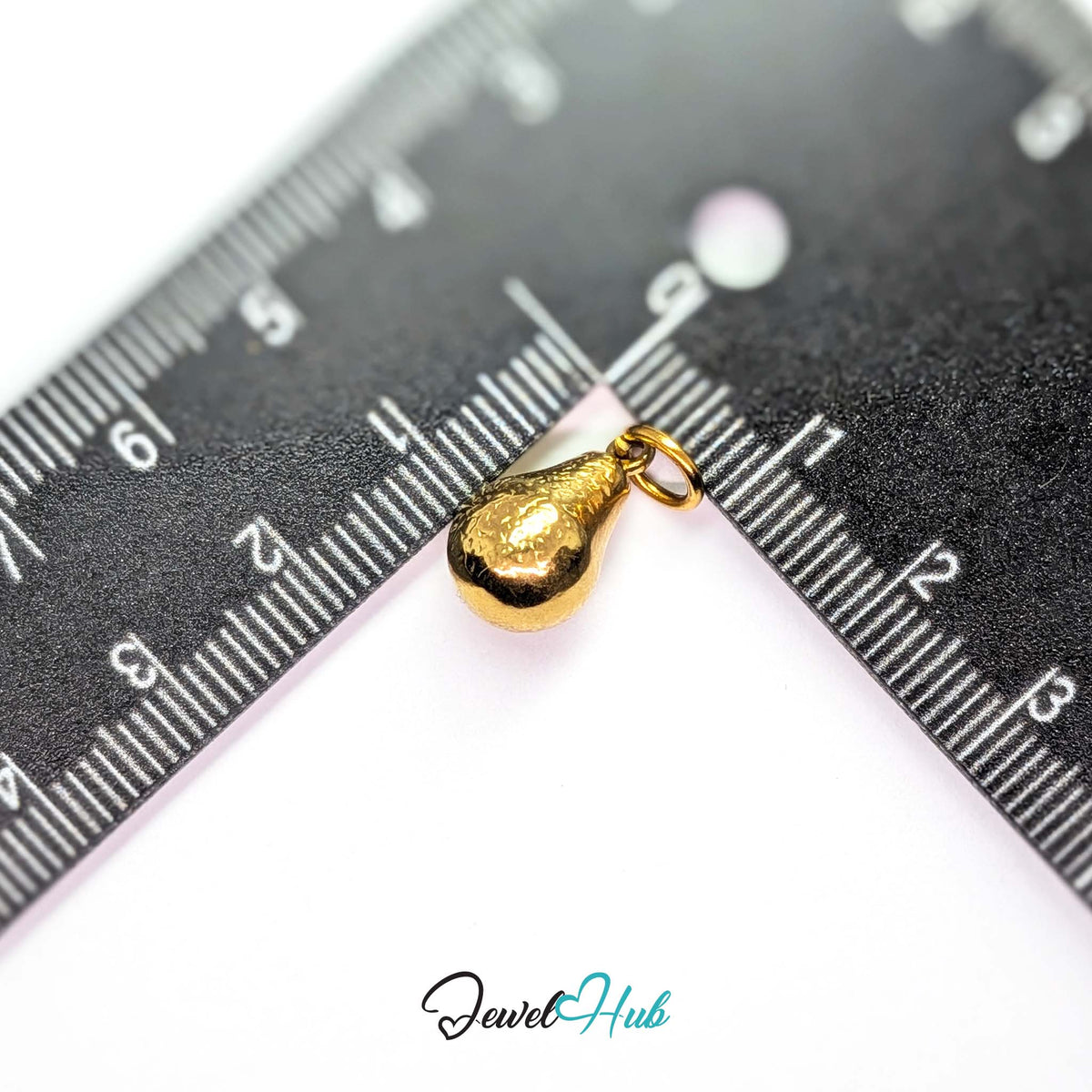 Hammered pear charm measured against a ruler at 9.1mm wide by 15mm tall - JewelHub