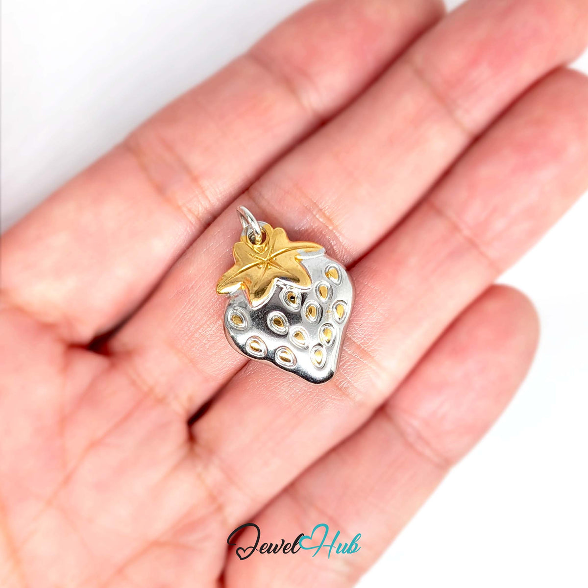 Two-tone strawberry charm held in a hand to show its size - JewelHub