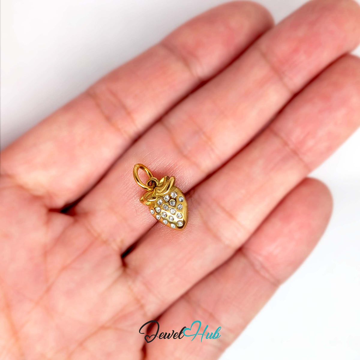 Crystal strawberry charm held in a hand to show its size - JewelHub