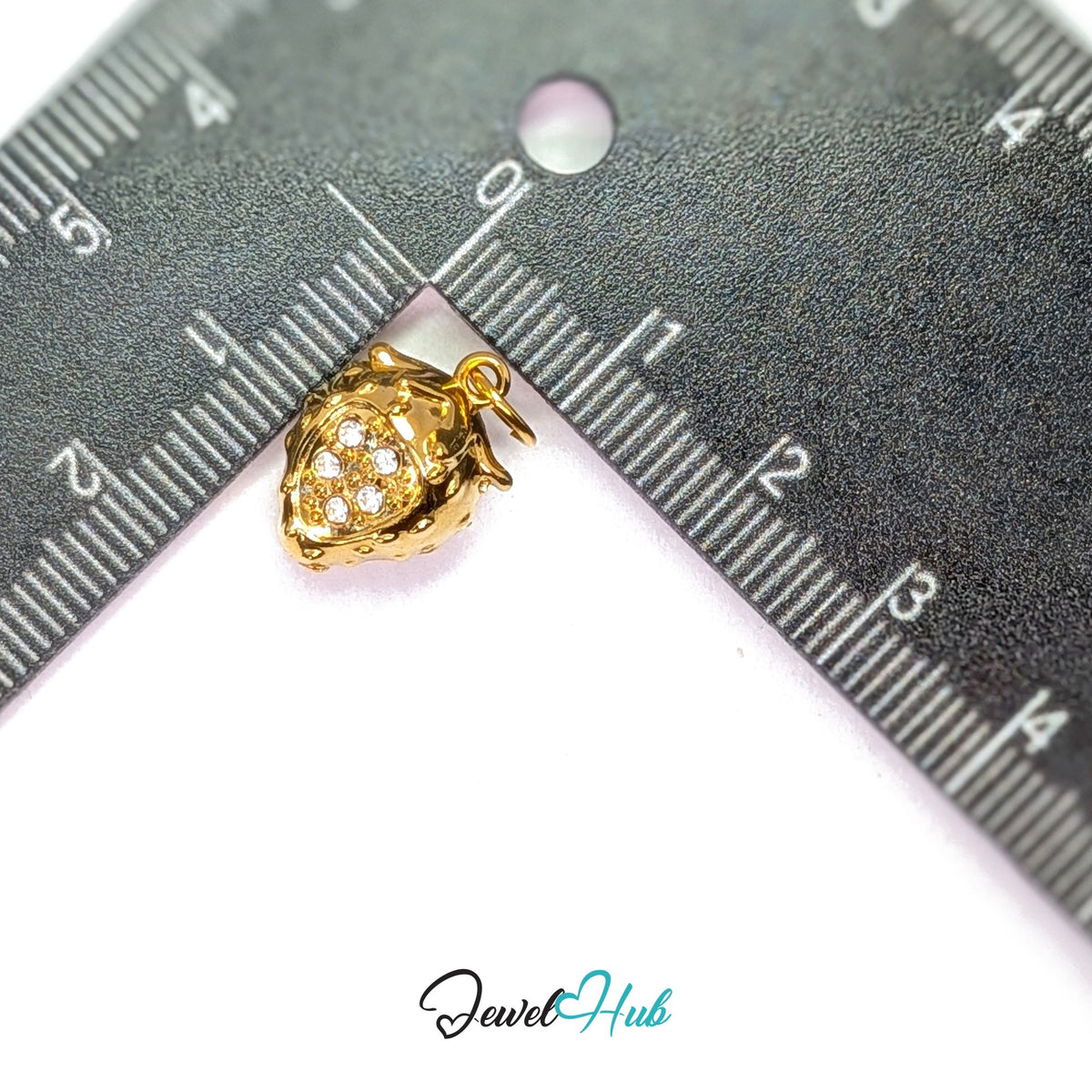 3D crystal strawberry charm measured against a ruler at 11mm wide by 15.8mm tall - JewelHub