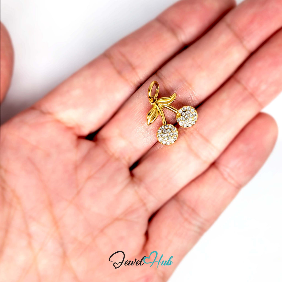 Crystal cherry charm held in a hand to show its size - JewelHub