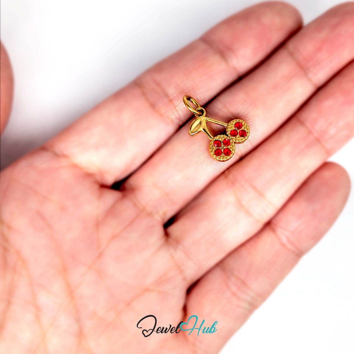 Red stone cluster cherry charm held in a hand to show its size - JewelHub