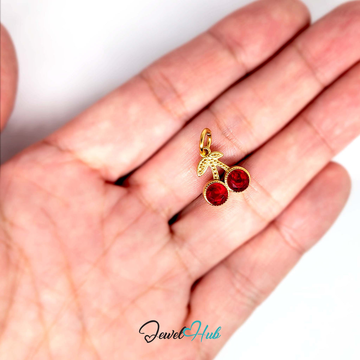 Big red gem cherry charm held in a hand to show its size - JewelHub