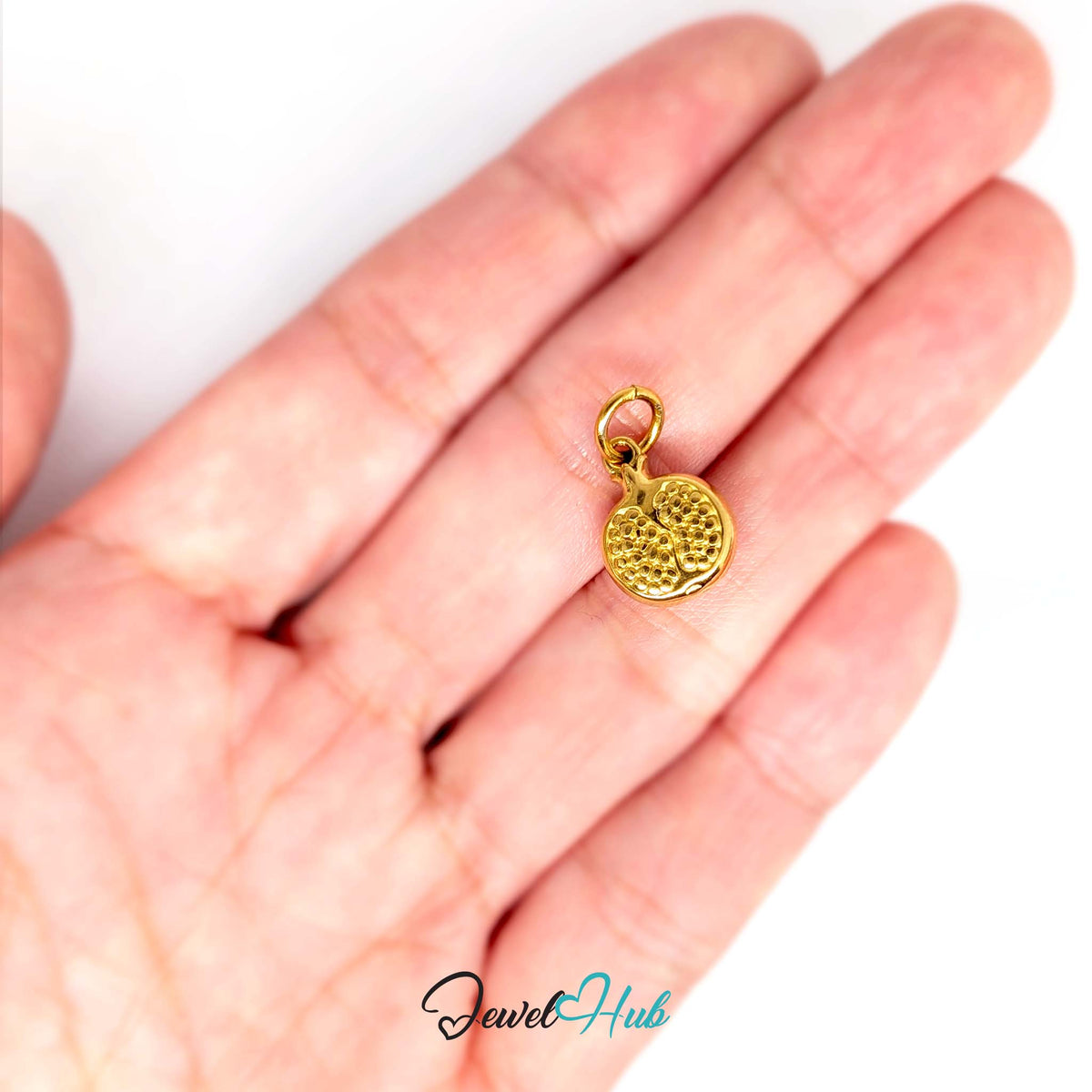Pomegranate charm held in a hand to show its size - JewelHub