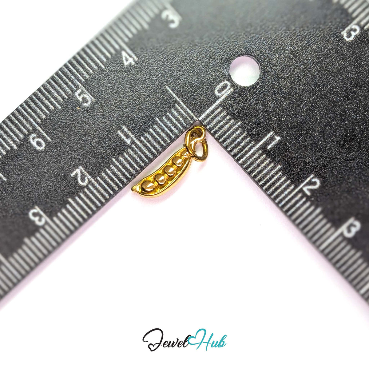Pea pod charm measured against a ruler at 5mm wide by 16.3mm tall - JewelHub