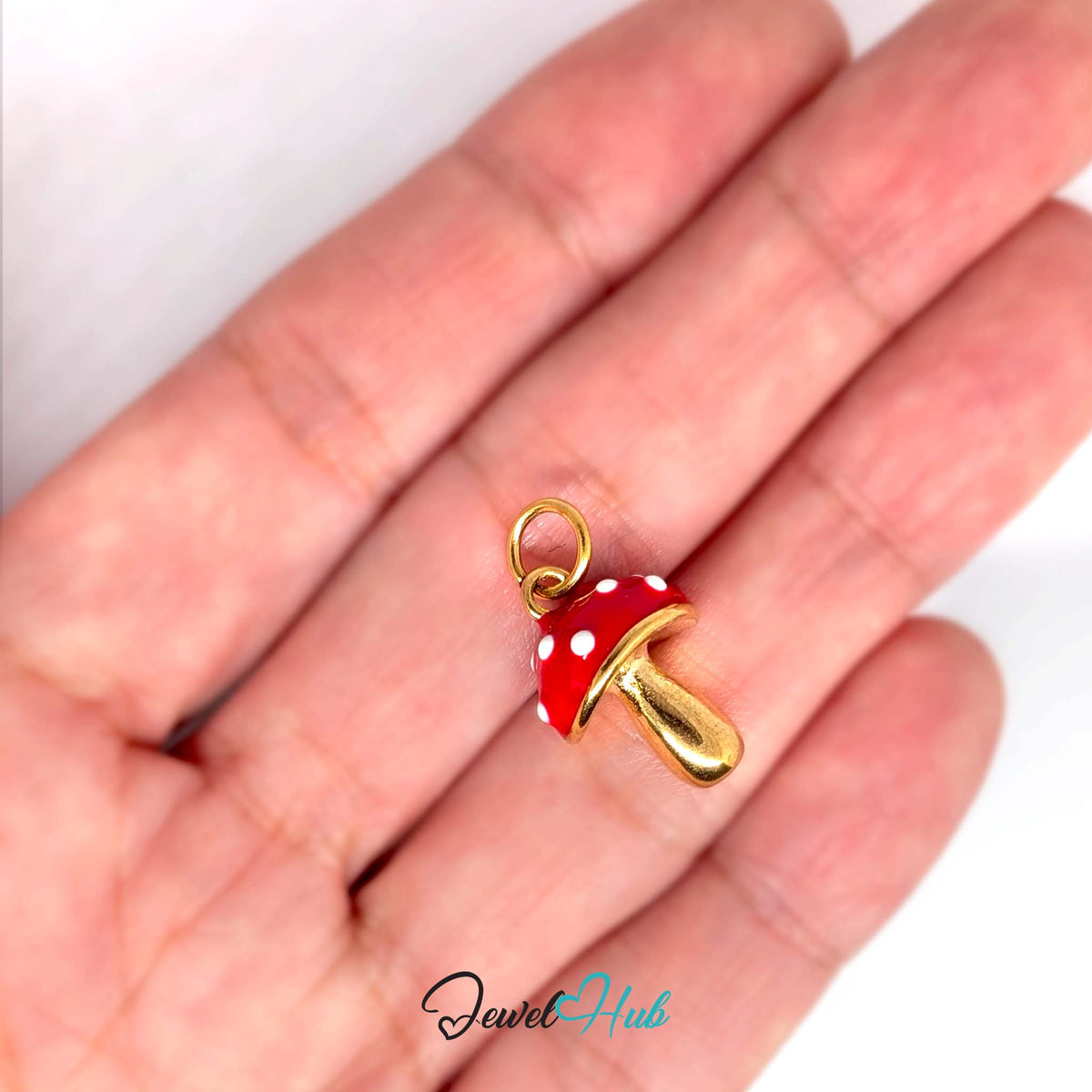 Red spotted mushroom charm held in a hand to show its size - JewelHub