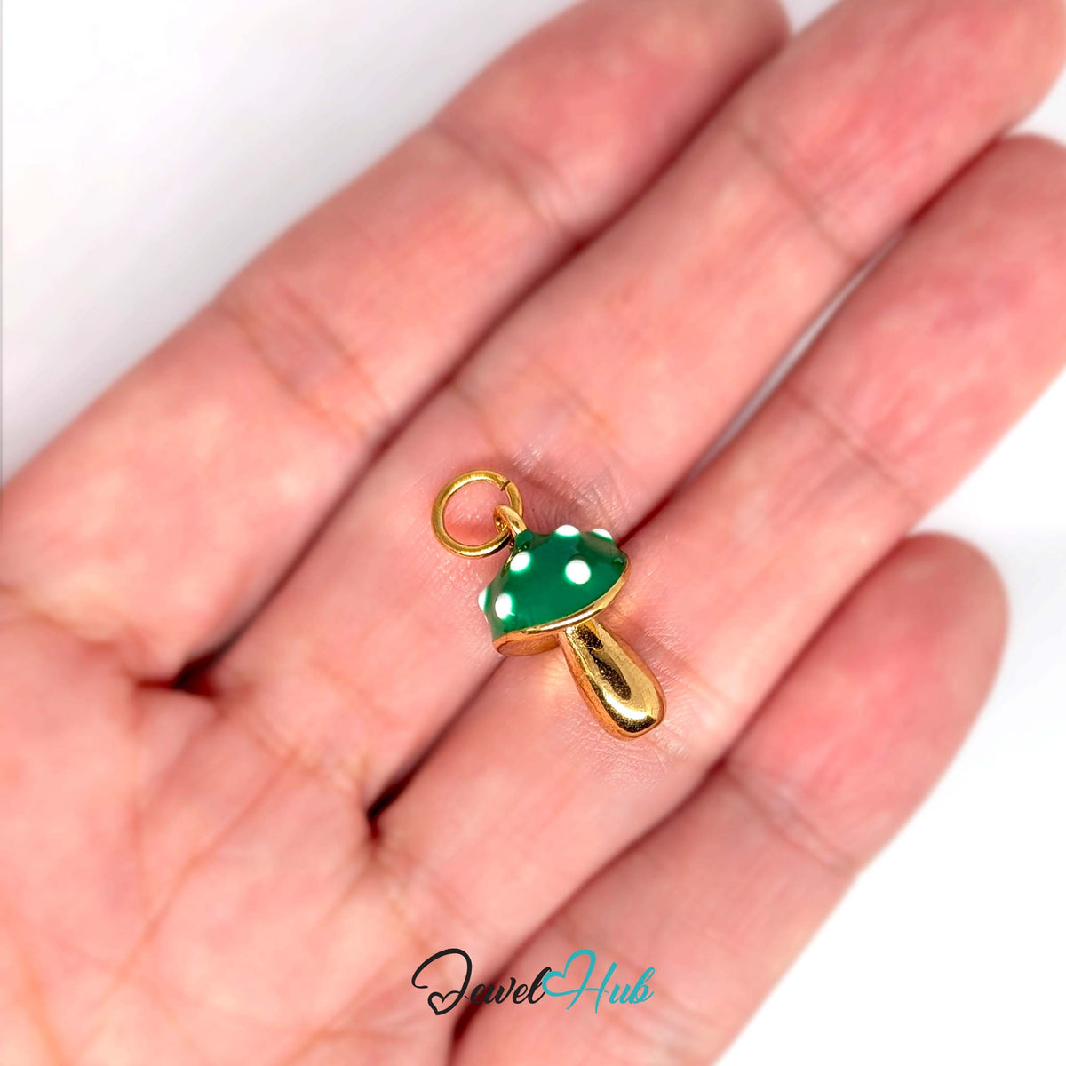 Green spotted mushroom charm held in a hand to show its size - JewelHub