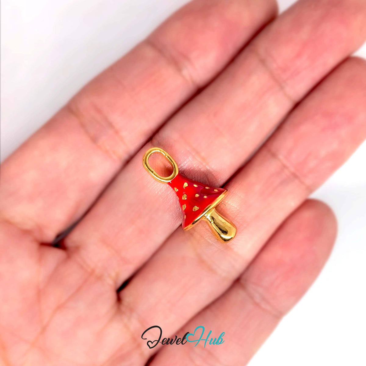Red gold dot mushroom charm held in a hand to show its size - JewelHub
