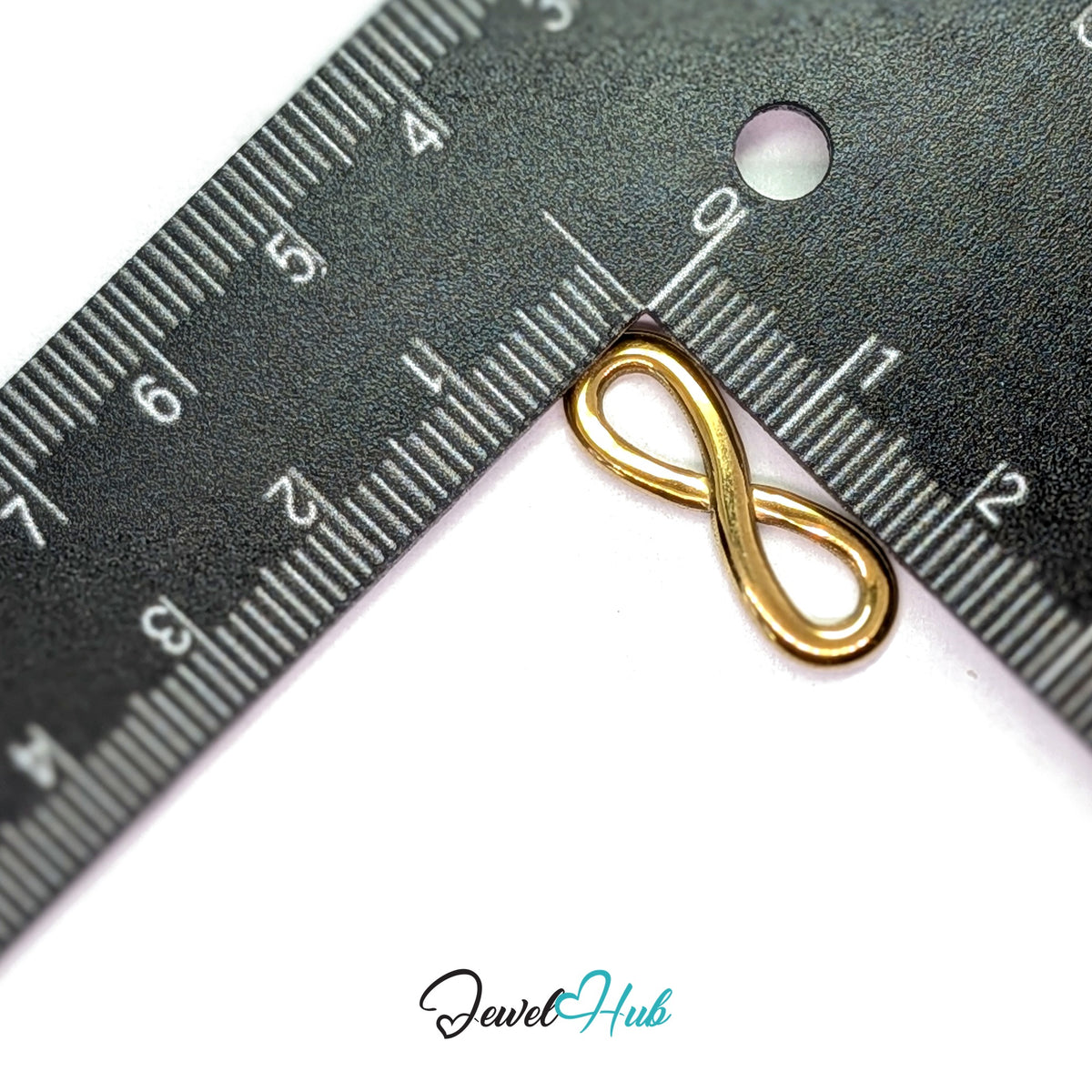Infinity charm measured against a ruler at 8.2mm wide by 23.8mm tall - JewelHub